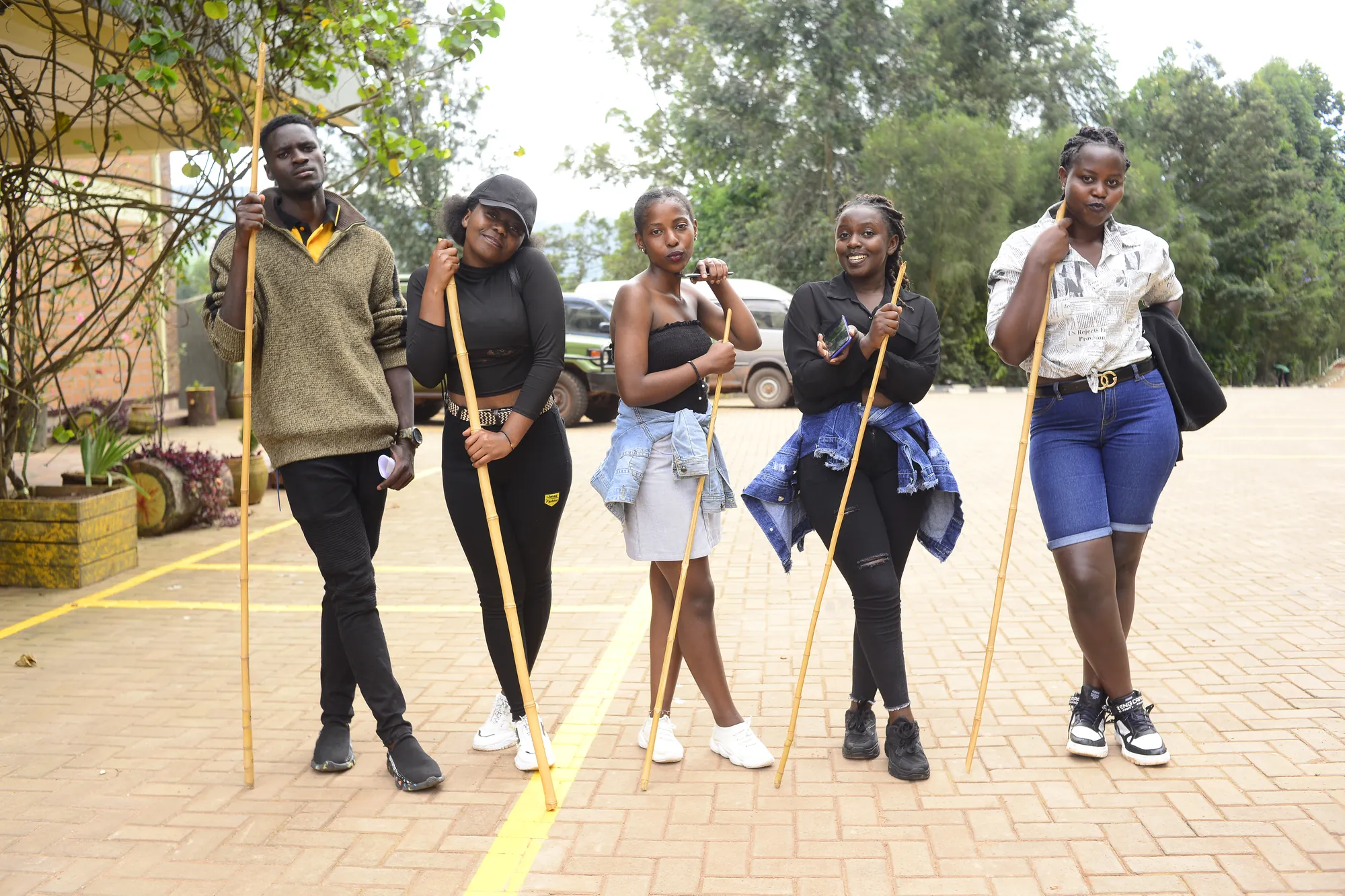 Five young visitors carrying walking sticks on the paved forecourt at the start of a guided hike