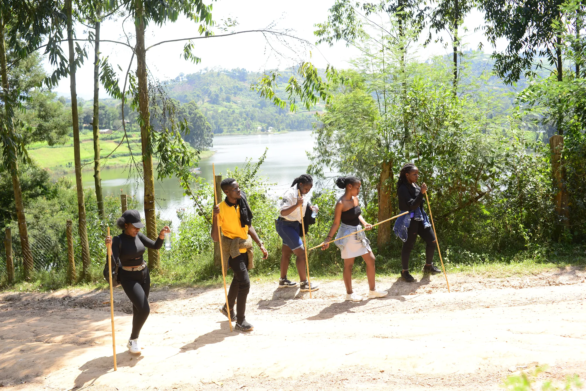 Hikers standing on a sandy clearing with Lake Bunyonyi visible through the trees behind them