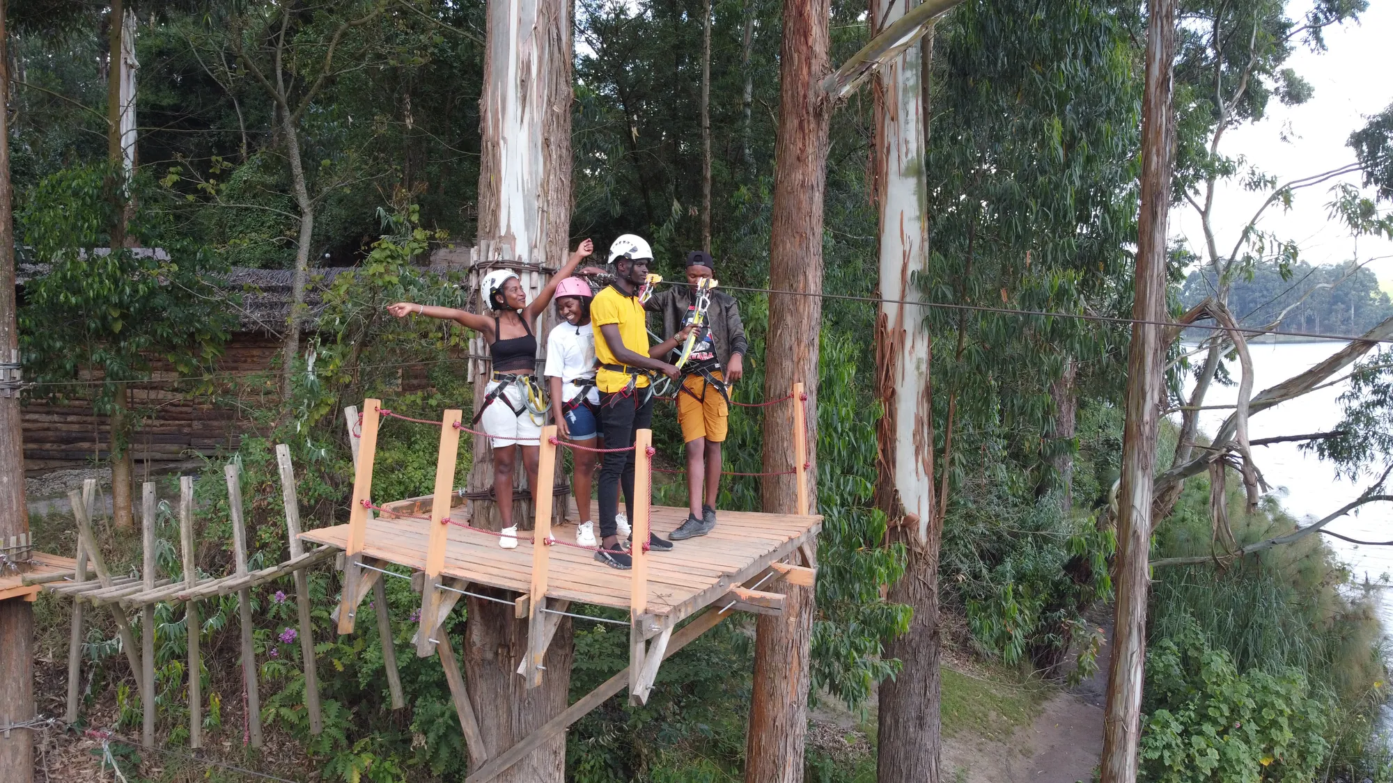A group in helmets and harnesses waiting on the wooden zip-line launch platform in the trees