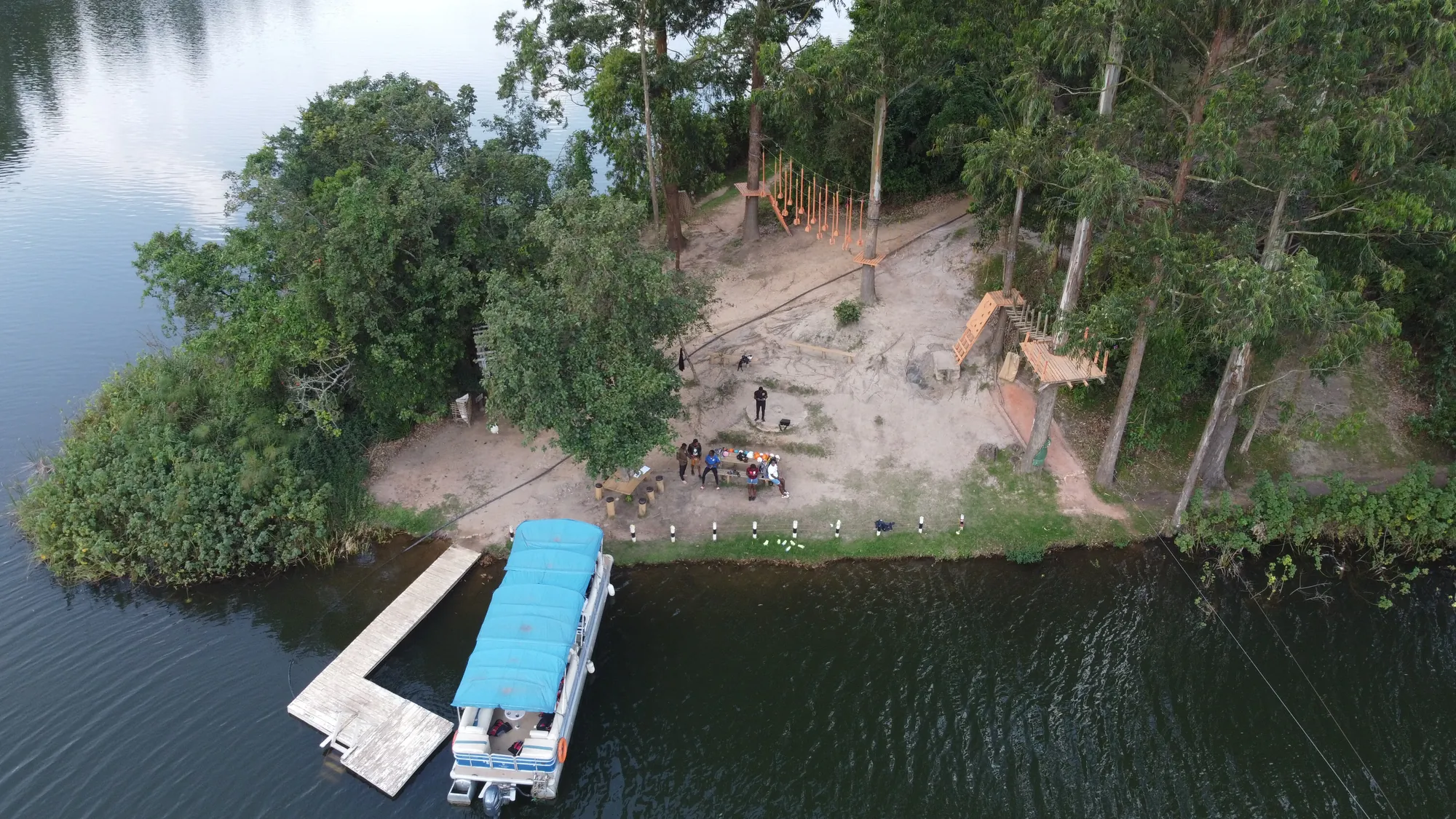 The zip-line landing area on the far shore with a moored blue-roofed boat at the jetty