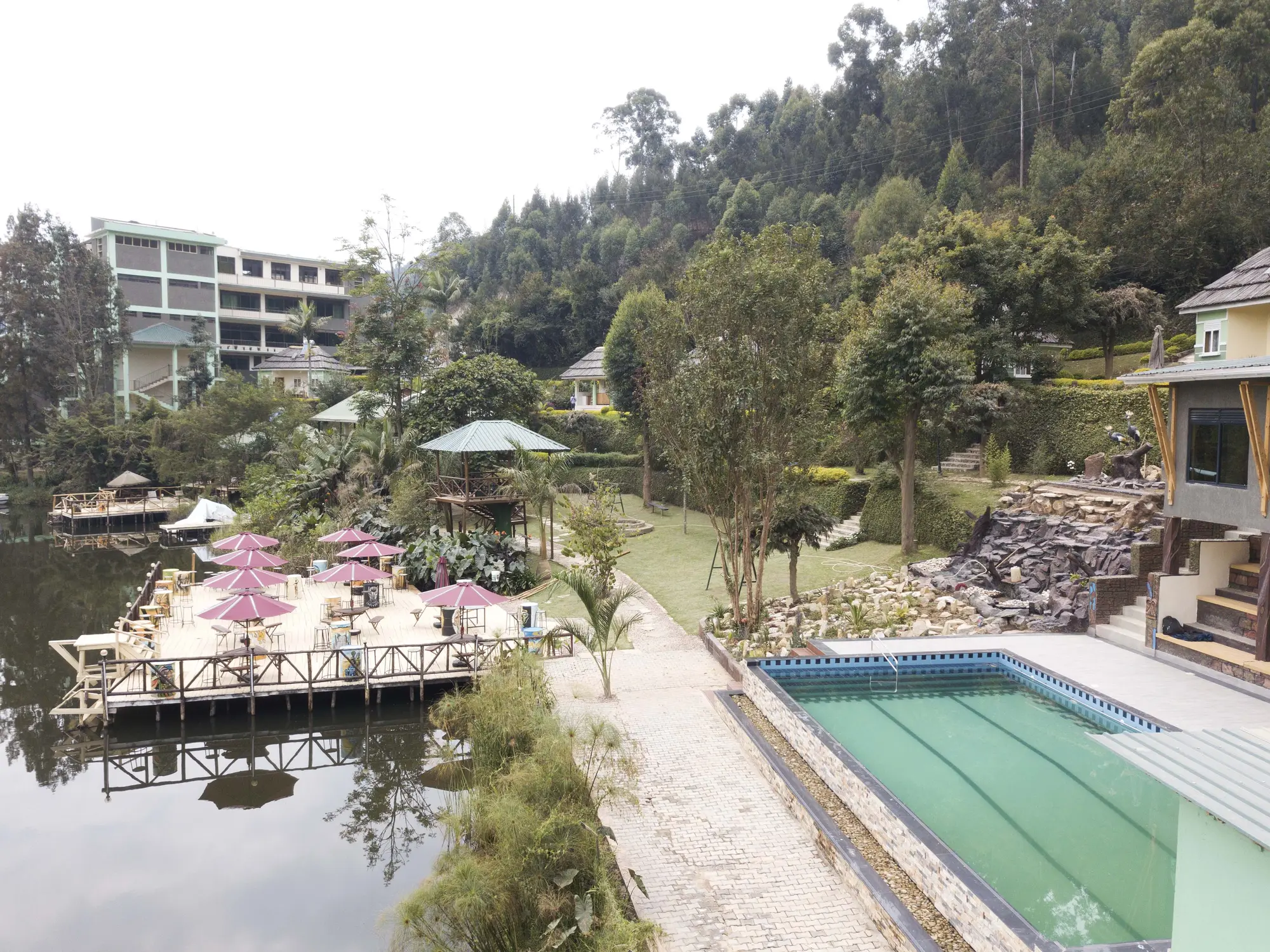 Aerial view of the pool and umbrella-shaded deck with the HOTEL sign on the building above