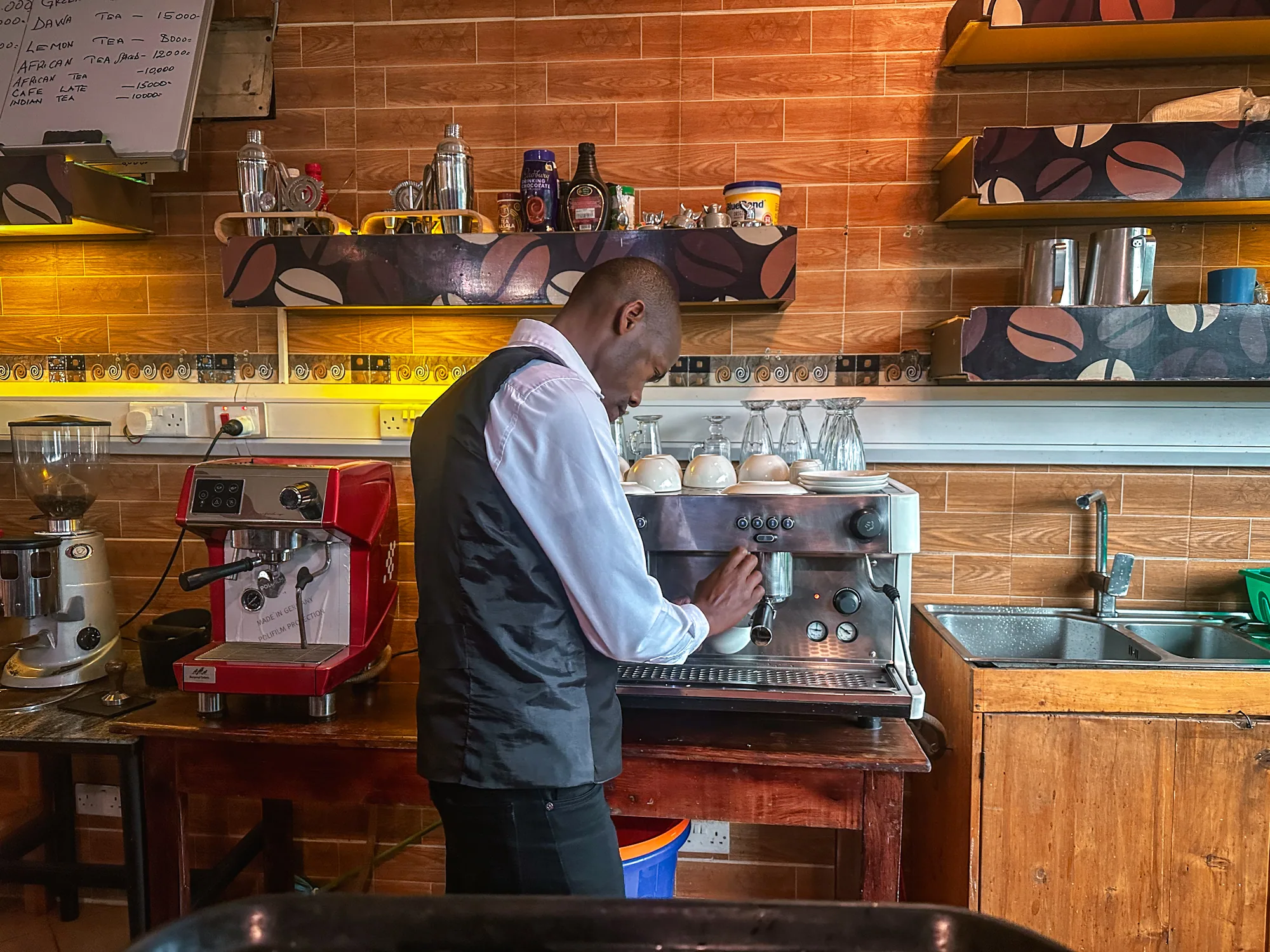 A barman working at the red espresso machine behind the timber coffee counter
