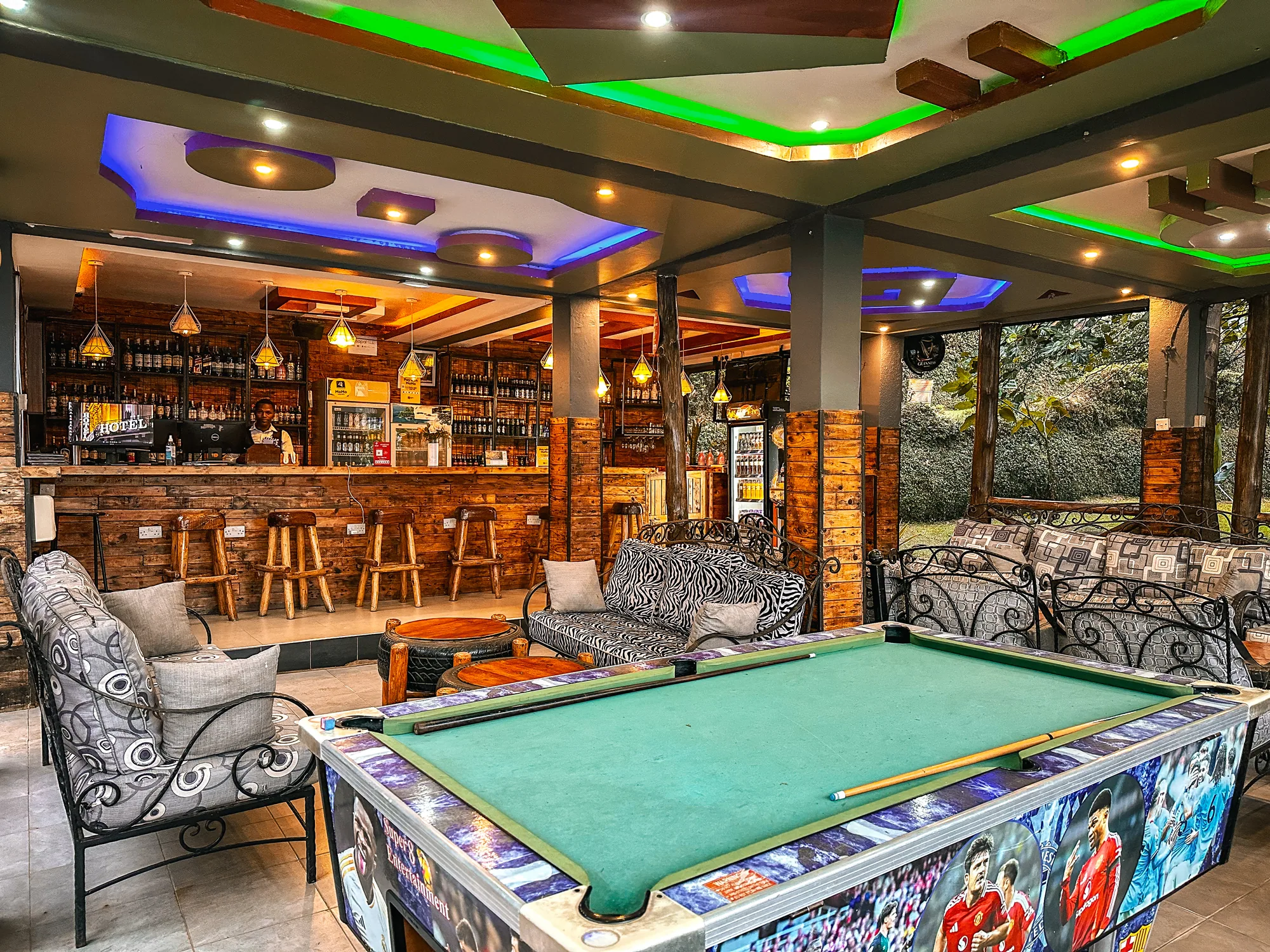 The bar lounge with a pool table, zebra-print sofas and wrought-iron chairs under a coloured ceiling