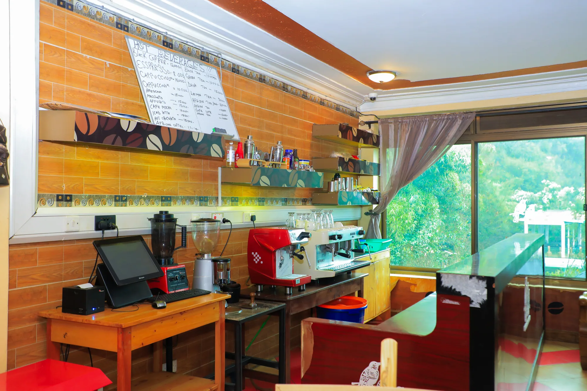 The coffee bar corner with espresso machines, till and a chalk menu board beside a window over the lake