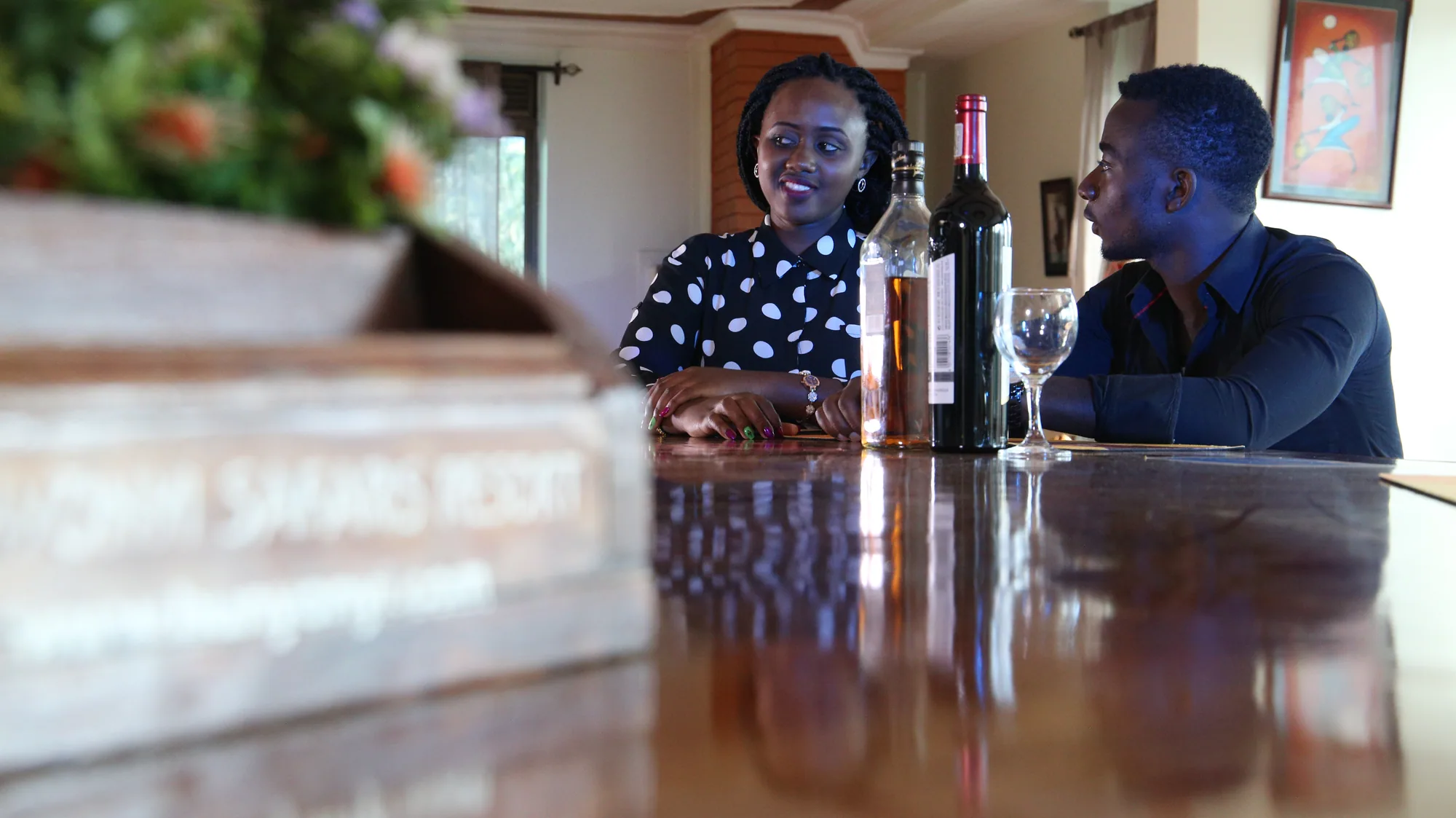 Two guests sitting with a bottle of wine and glasses at the polished bar counter