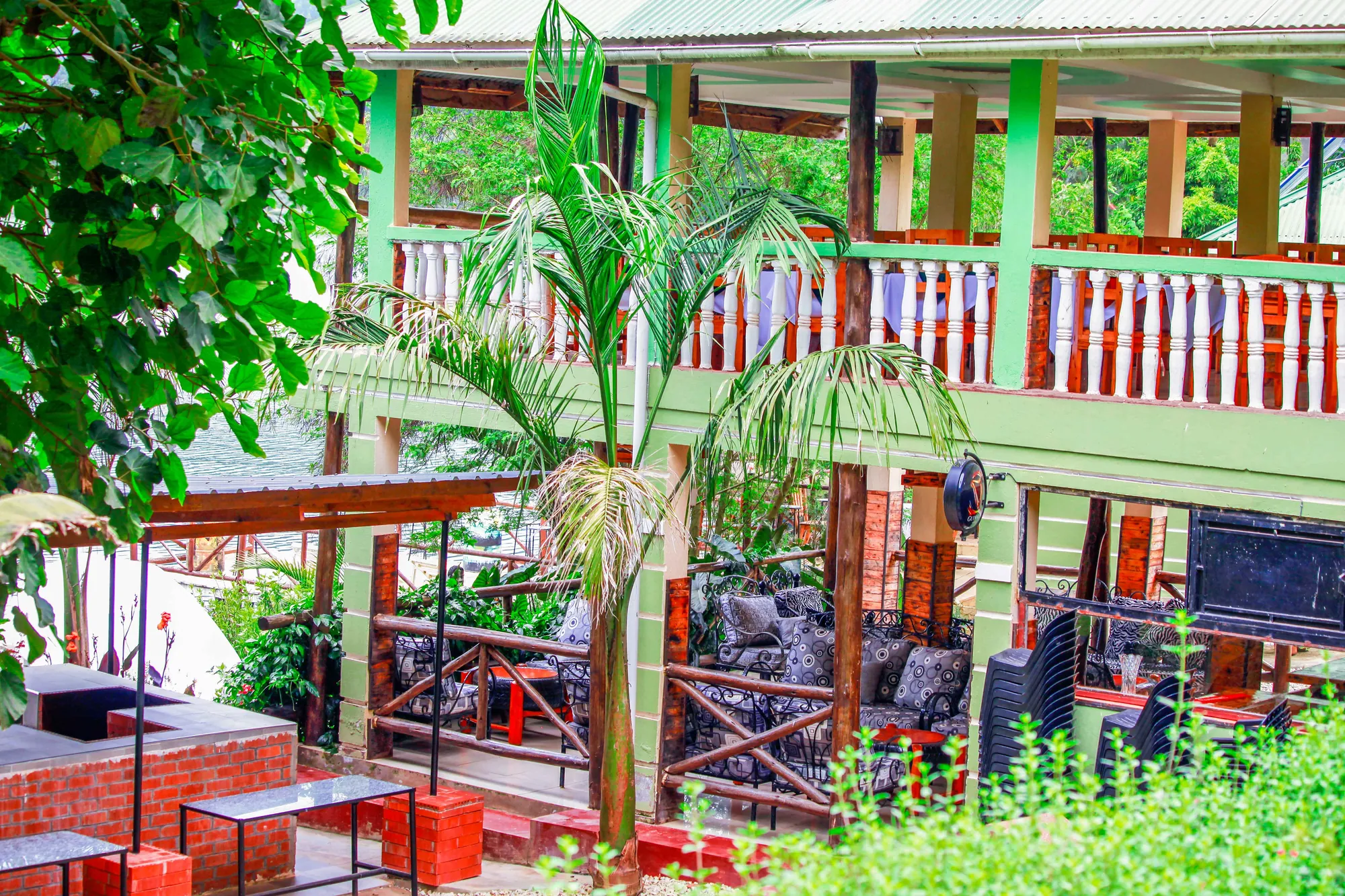 The green-railed garden bar and grill terrace with a palm and stone planters in front