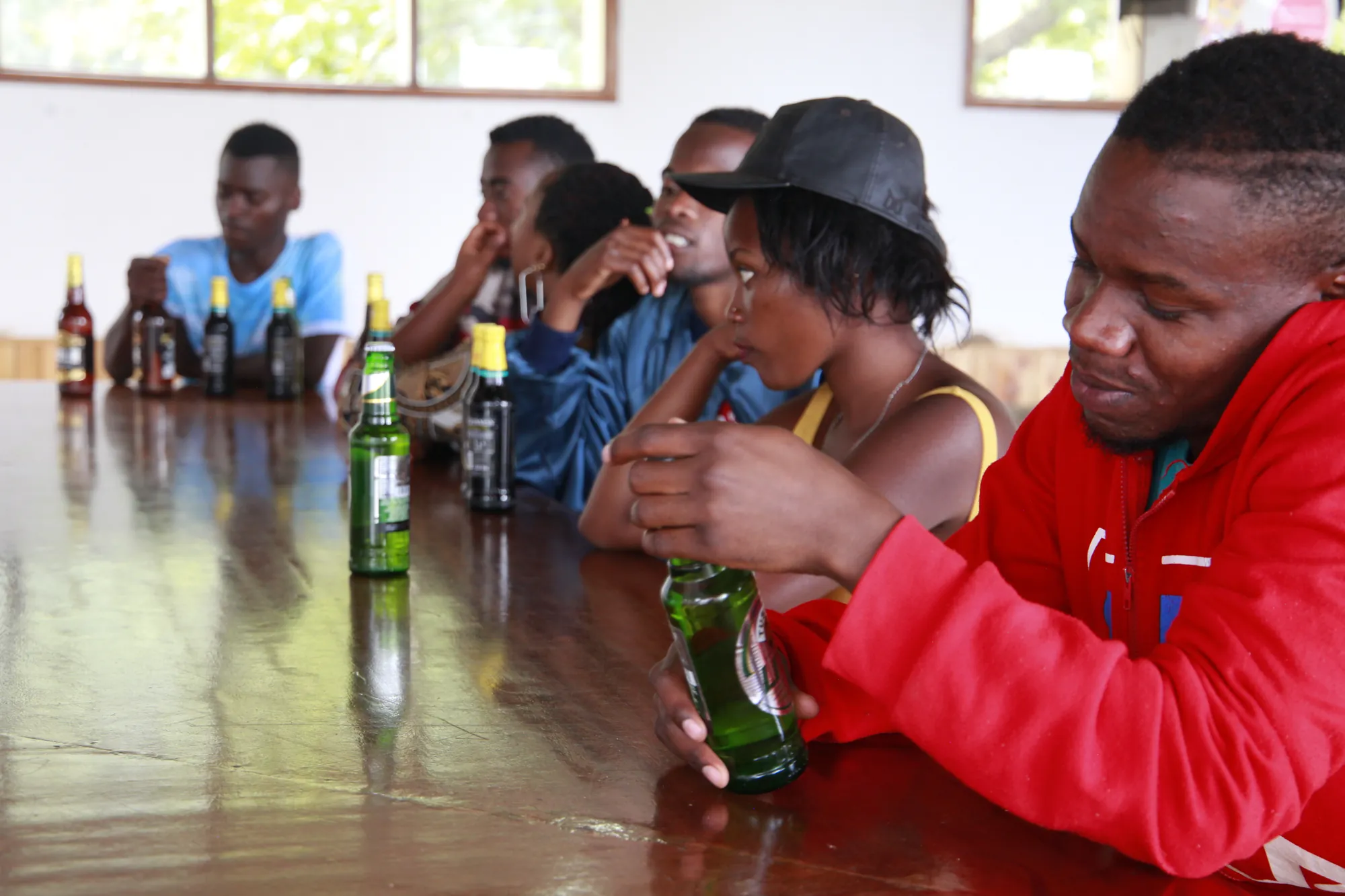Guests sitting along the bar counter with bottled drinks, talking