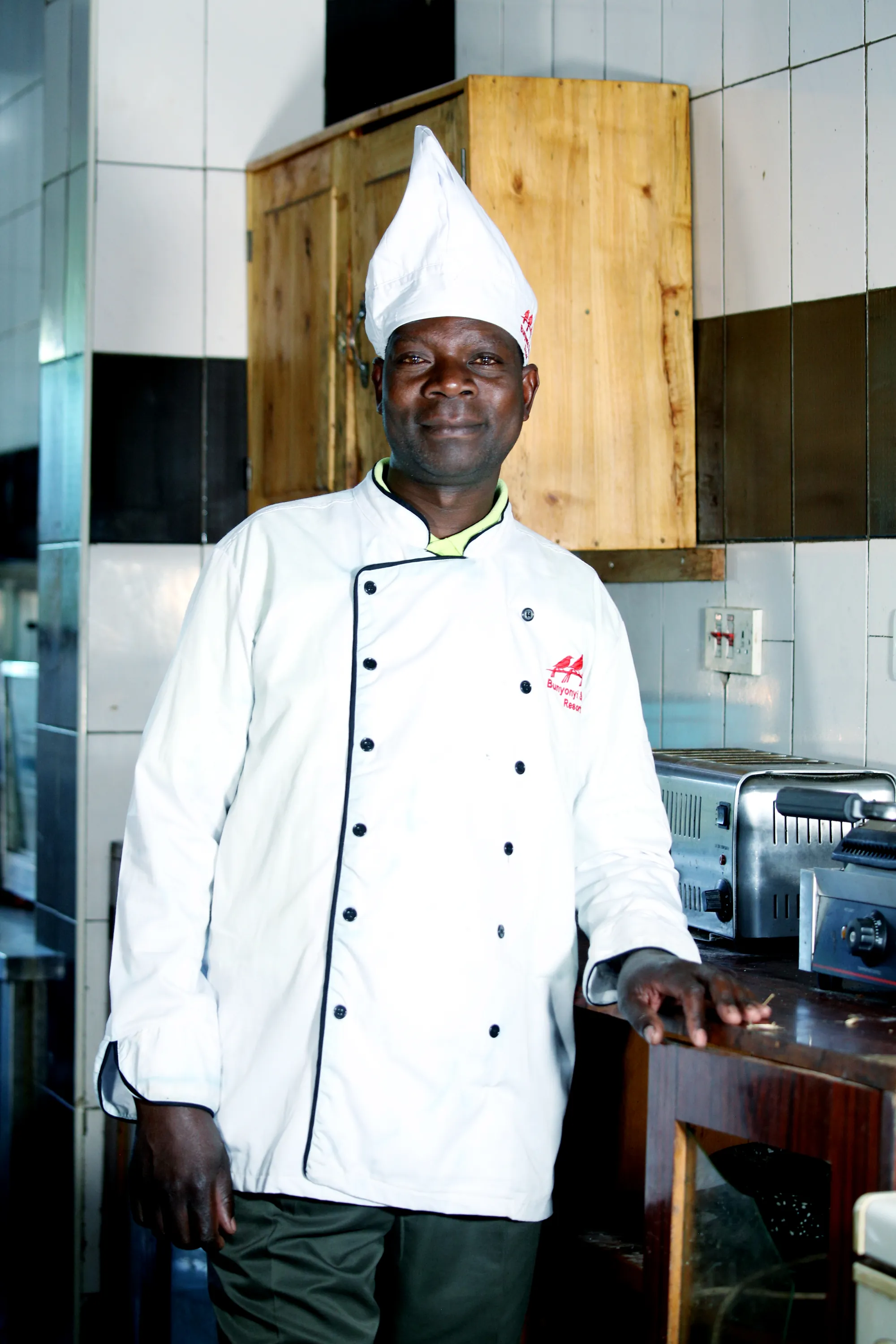 A chef in whites and a tall hat standing in the stainless-steel kitchen