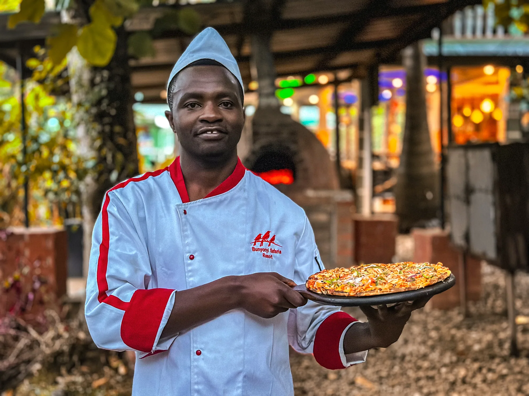 A chef presenting a pizza on a tray under the pizza terrace roof