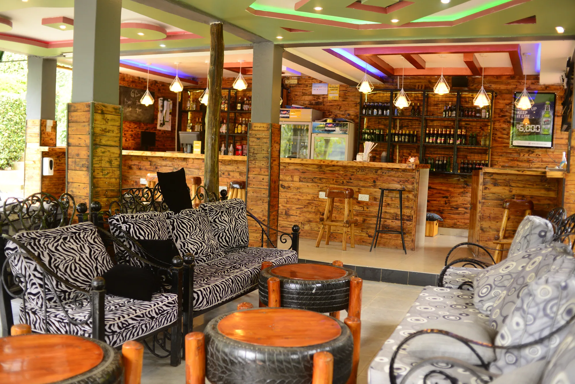 The bar and its lounge seating with patterned sofas and drum tables, seen across the room