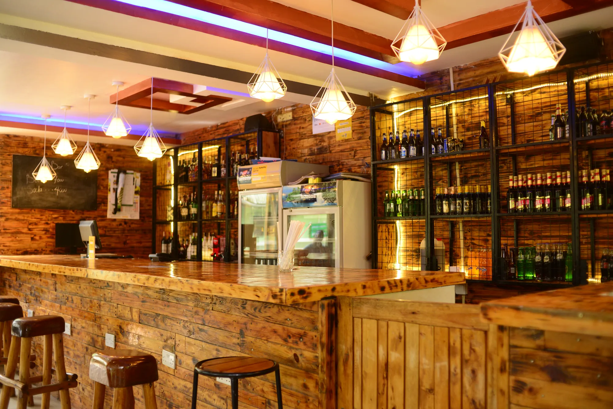 The empty bar counter and stools with pendant lights and stocked shelves