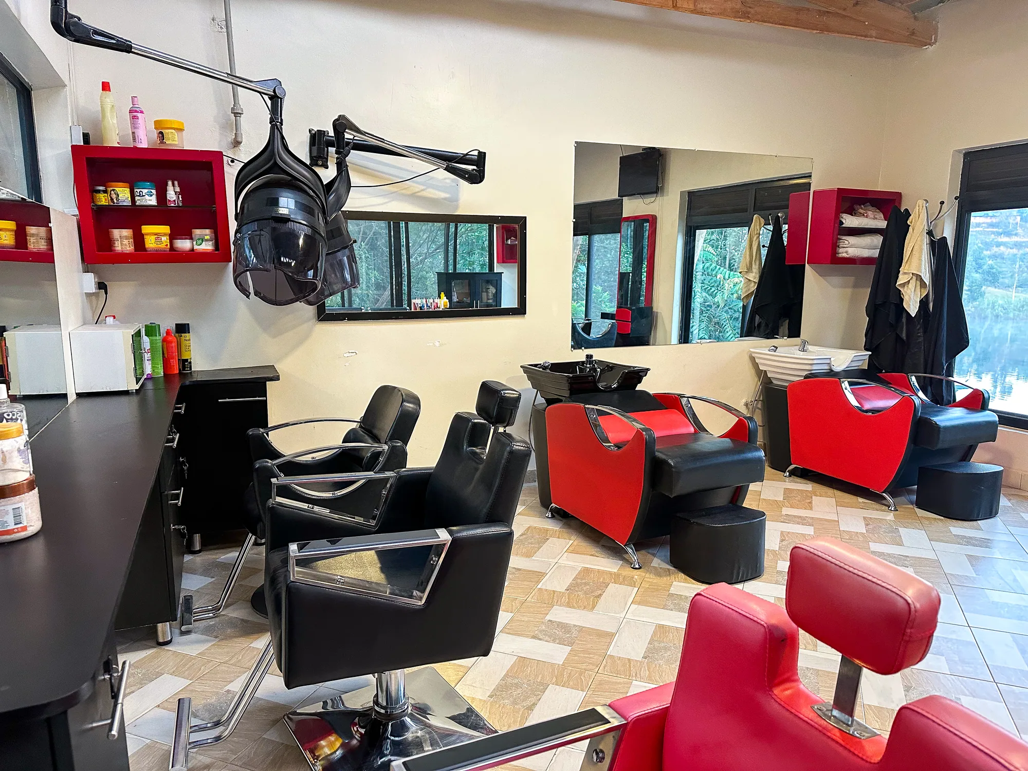 The salon with black styling chairs, mirrors, red barber chairs and a washing basin