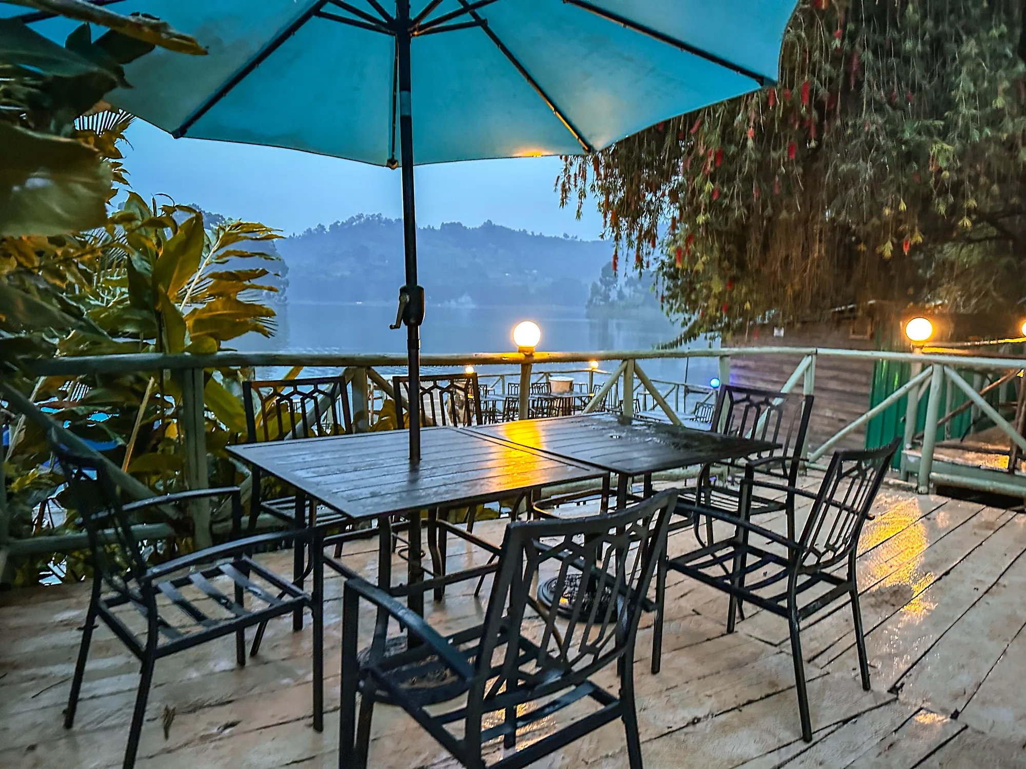 Timber-decked terrace tables under a blue parasol in overcast weather