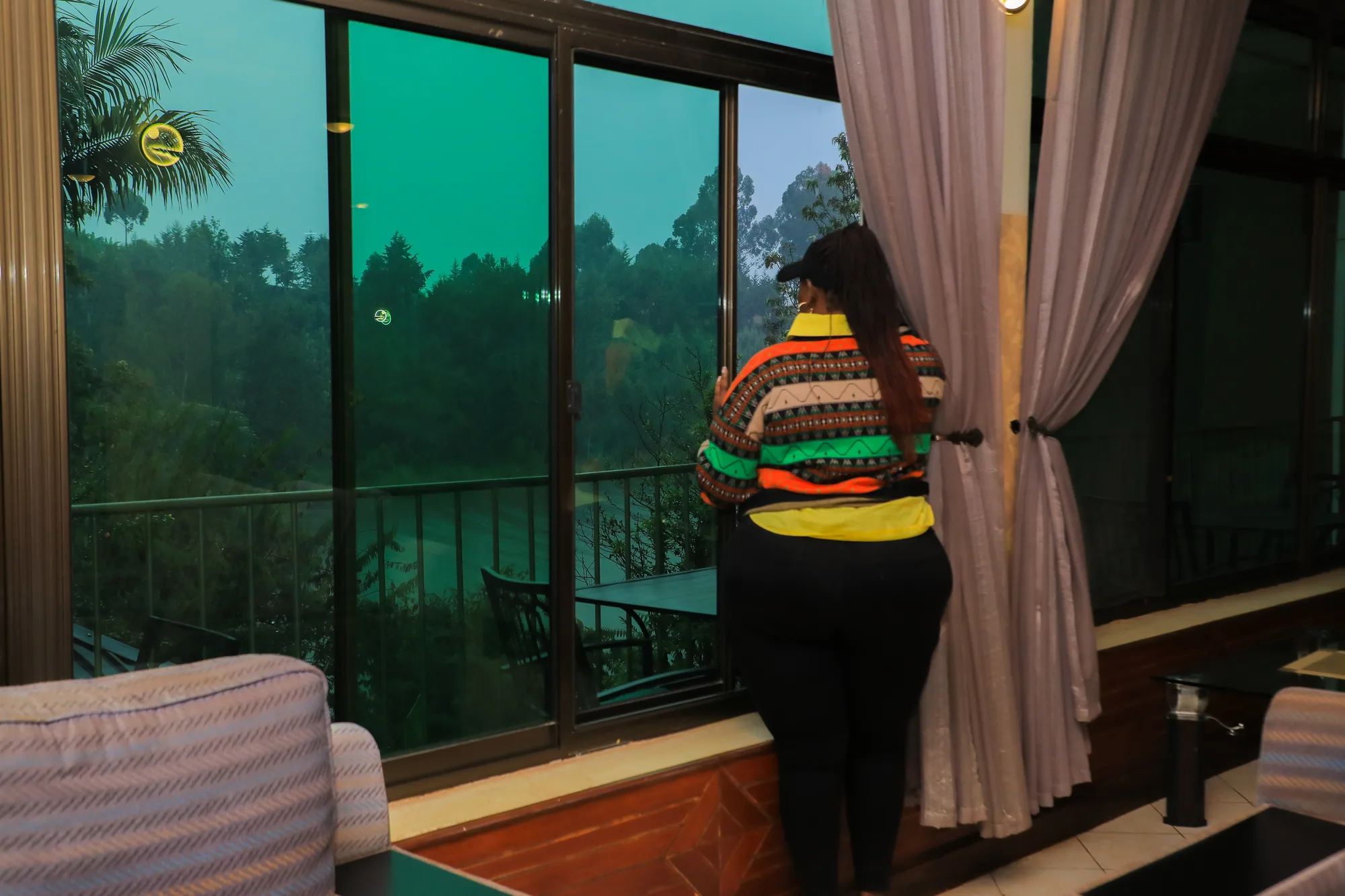 A guest standing at an open balcony door looking out to the trees