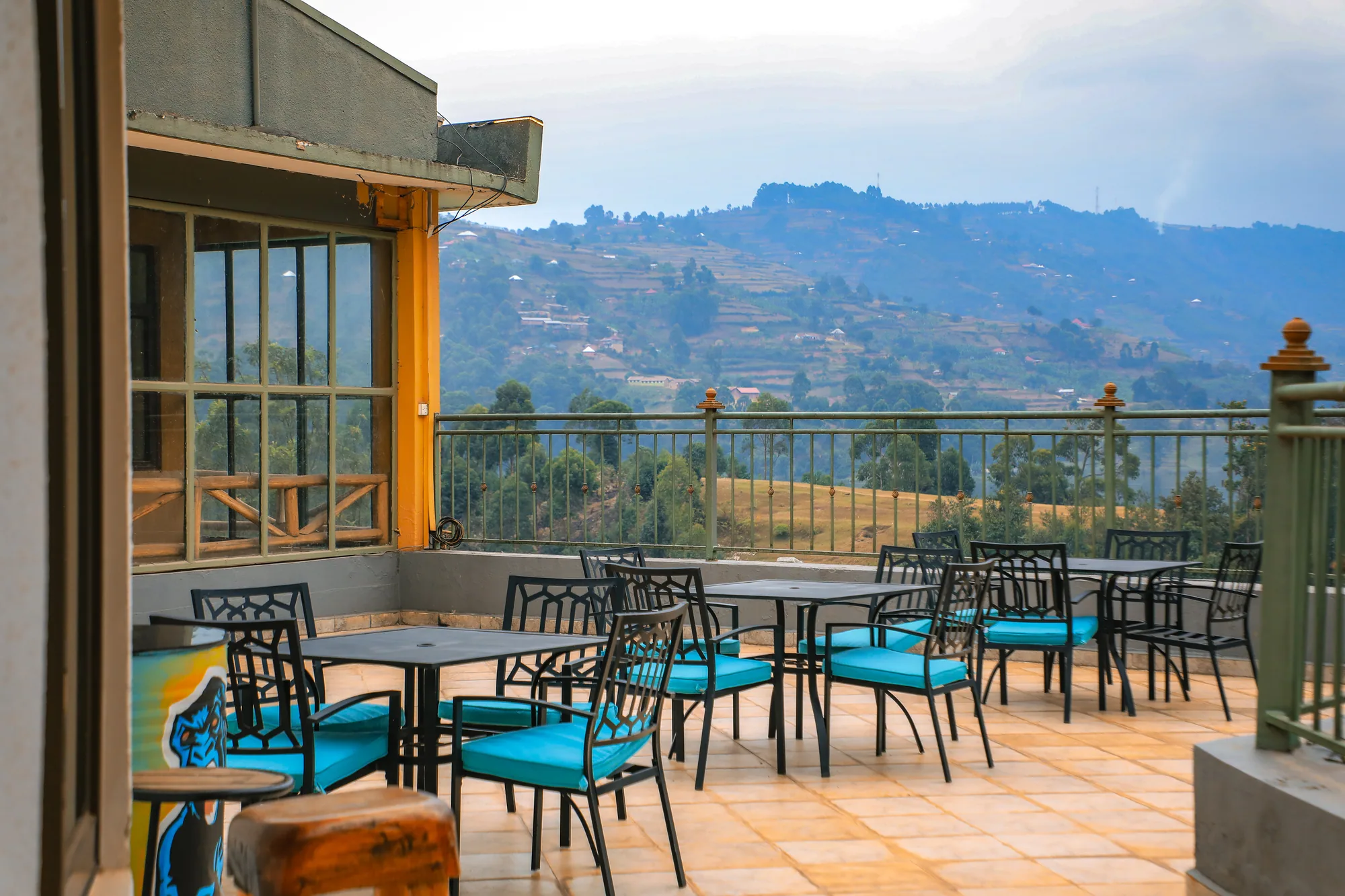 The tiled terrace with turquoise-cushioned chairs looking across the lake to distant hills