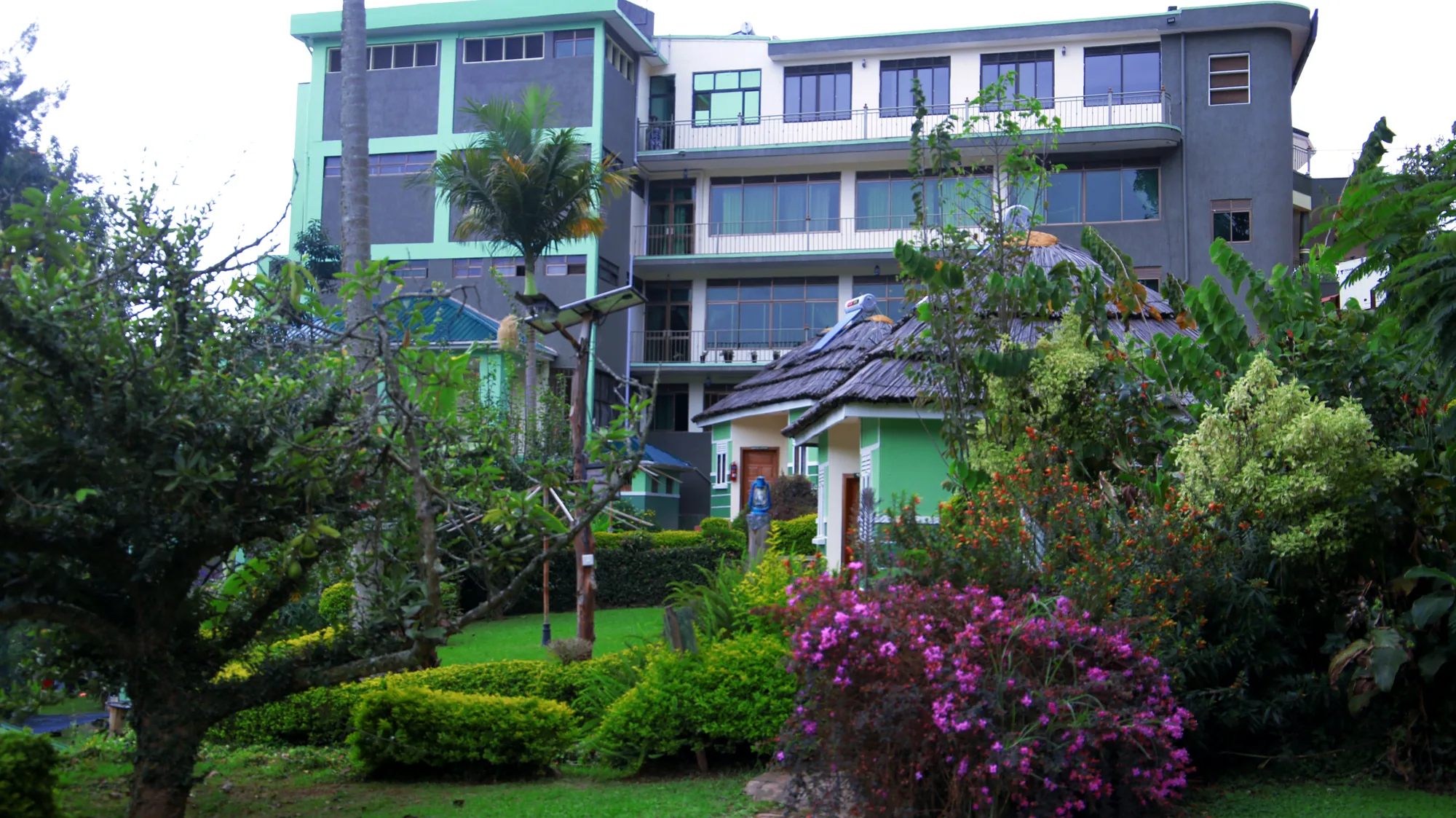 The main hotel block with balconies, palms and flowering garden beds in the foreground
