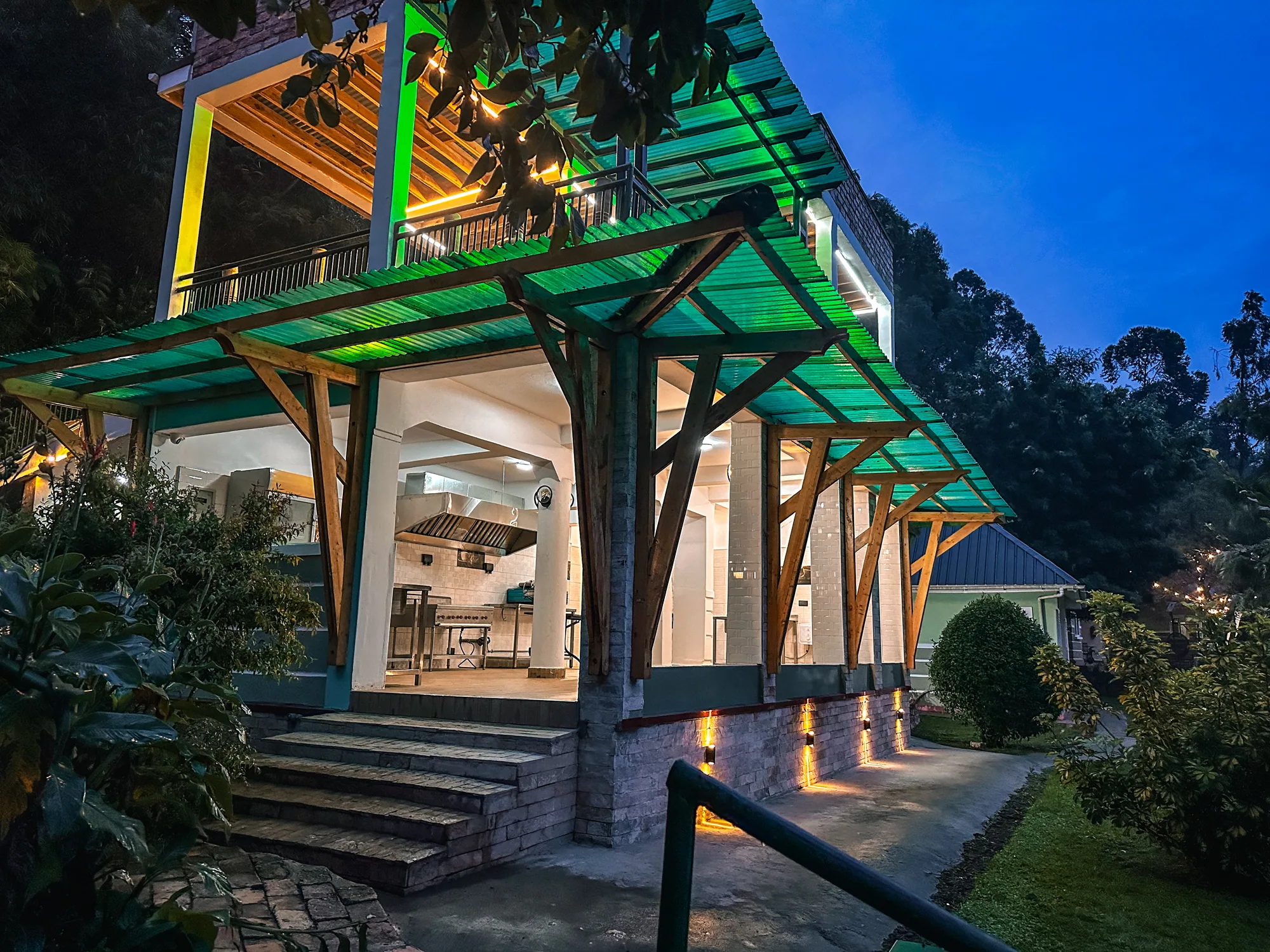 The lit entrance porch of the events centre in the evening, with green roof beams