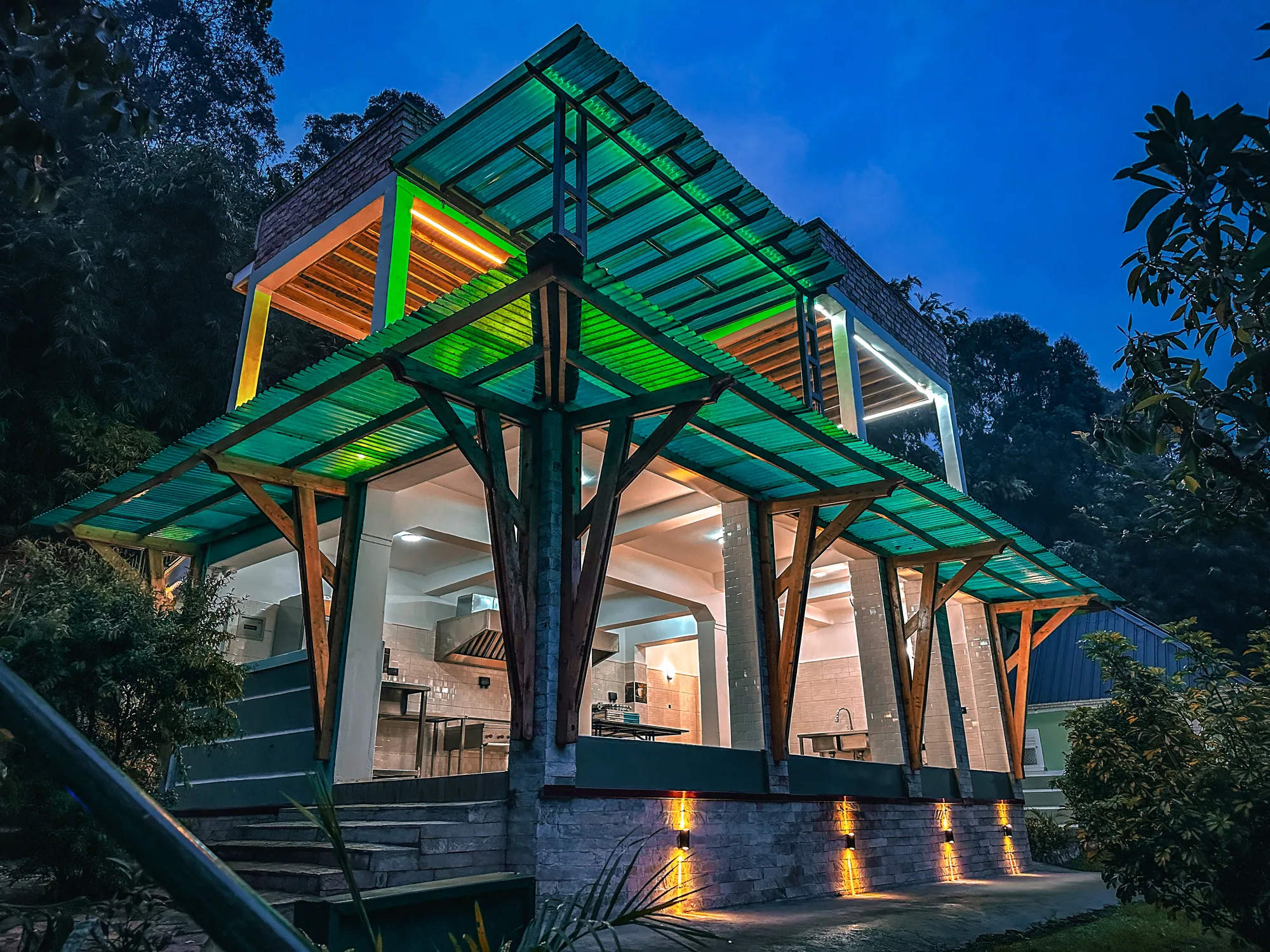 The green-roofed timber and glass entrance canopy of the events centre lit at night