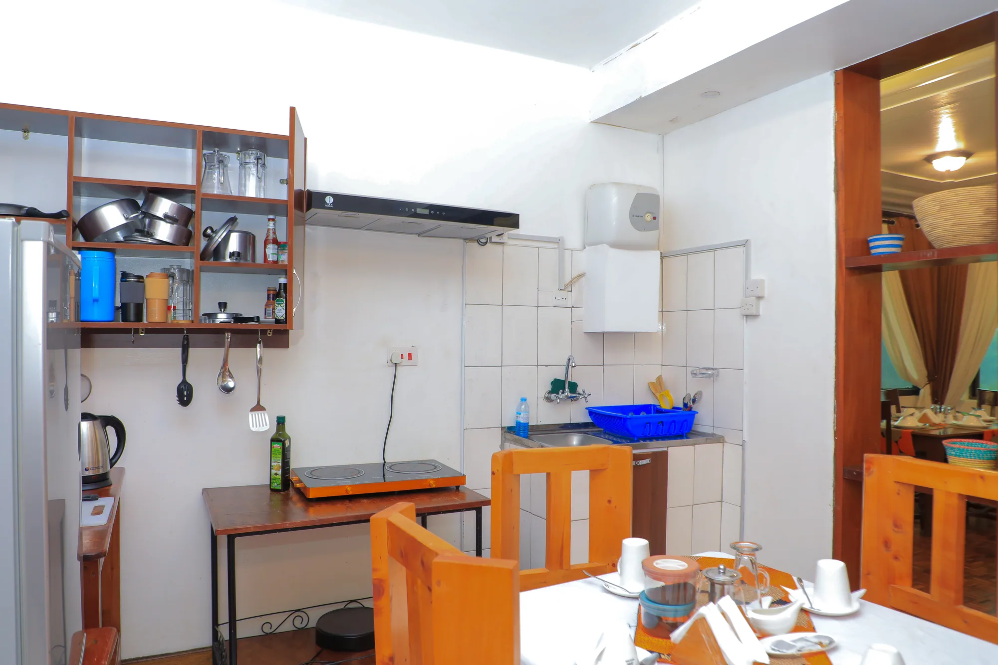 A self-catering kitchen with open shelves of pans and a laid table in the foreground