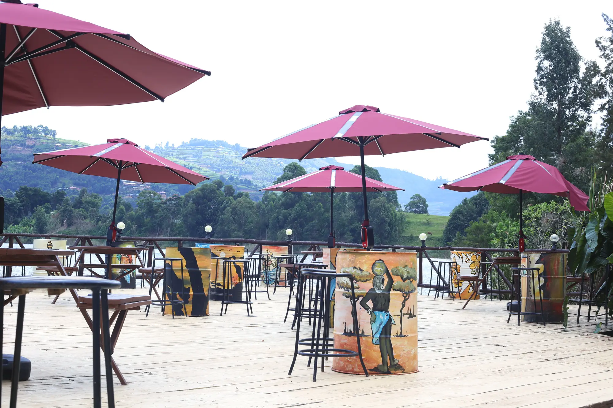 Outdoor terrace with bar tables, stools and burgundy parasols looking out to the hills