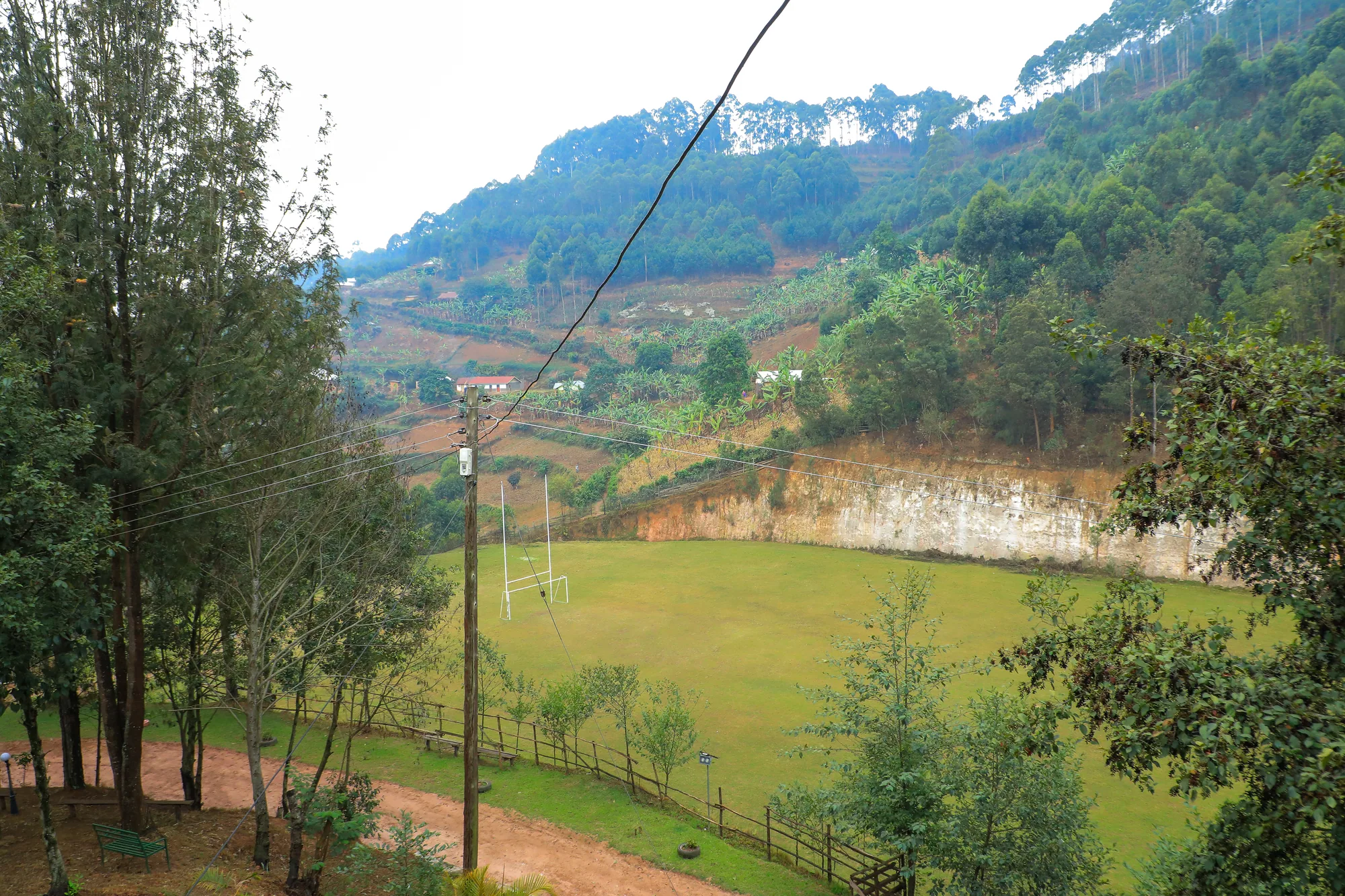 The hilltop lawn ringed by trees, with farmed hillsides and a quarry cut behind