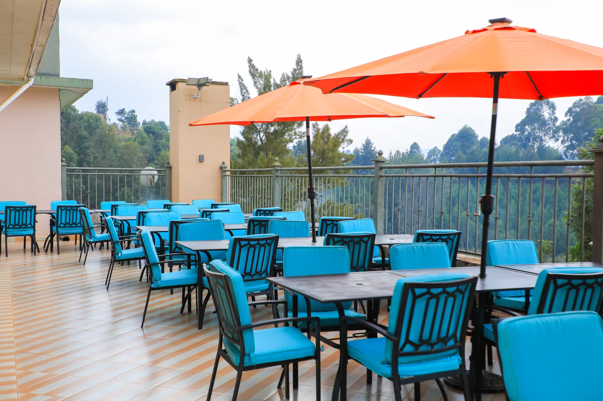 Terrace seating under red parasols on a tiled floor beside the building
