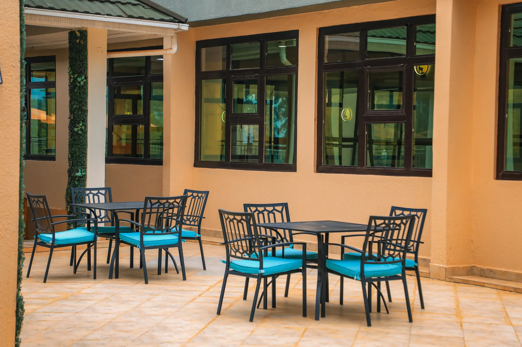 Tables and chairs on the paved veranda under the arcade of a cream building