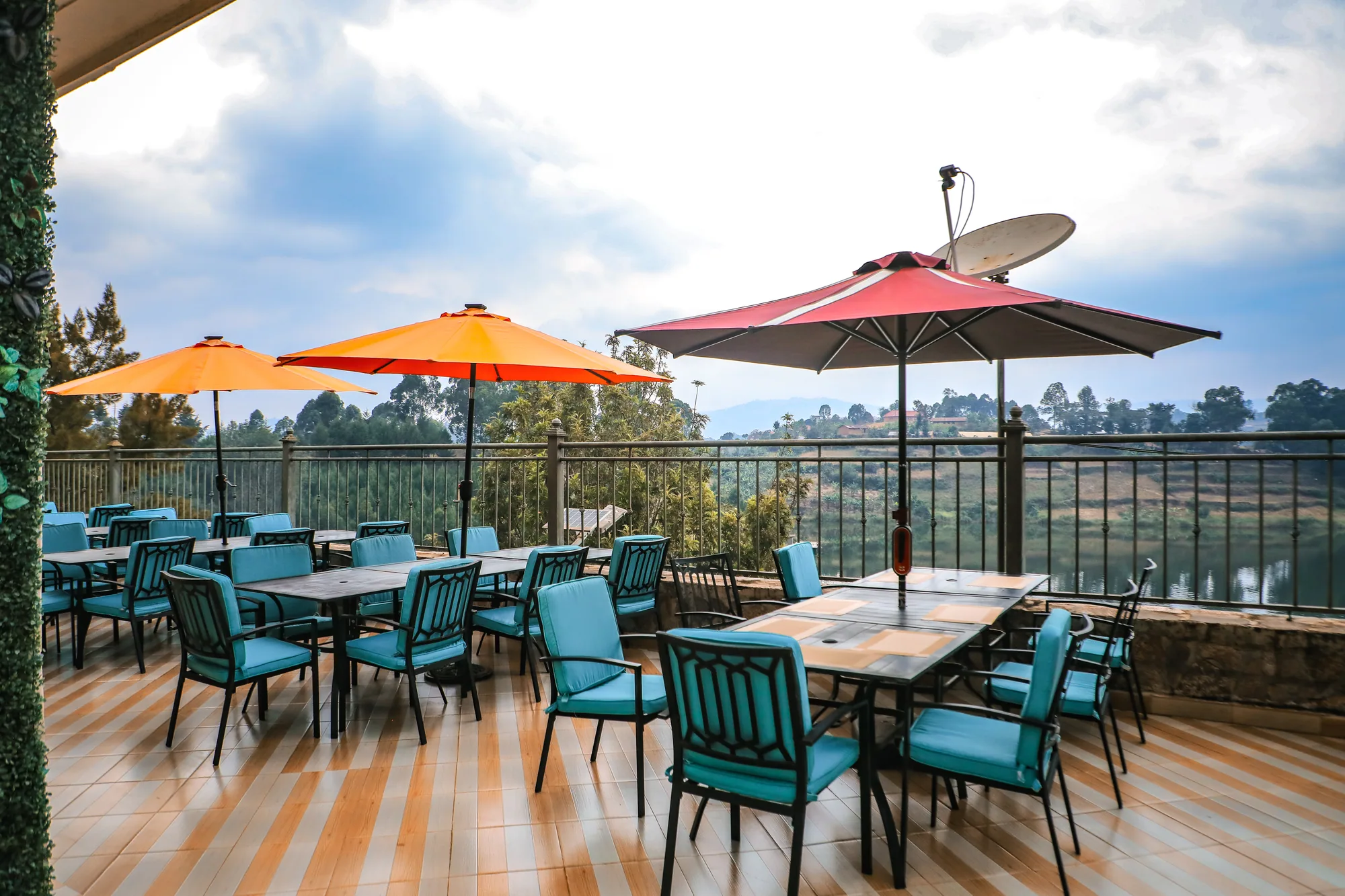 Terrace tables under orange and maroon parasols on new timber decking above the lake