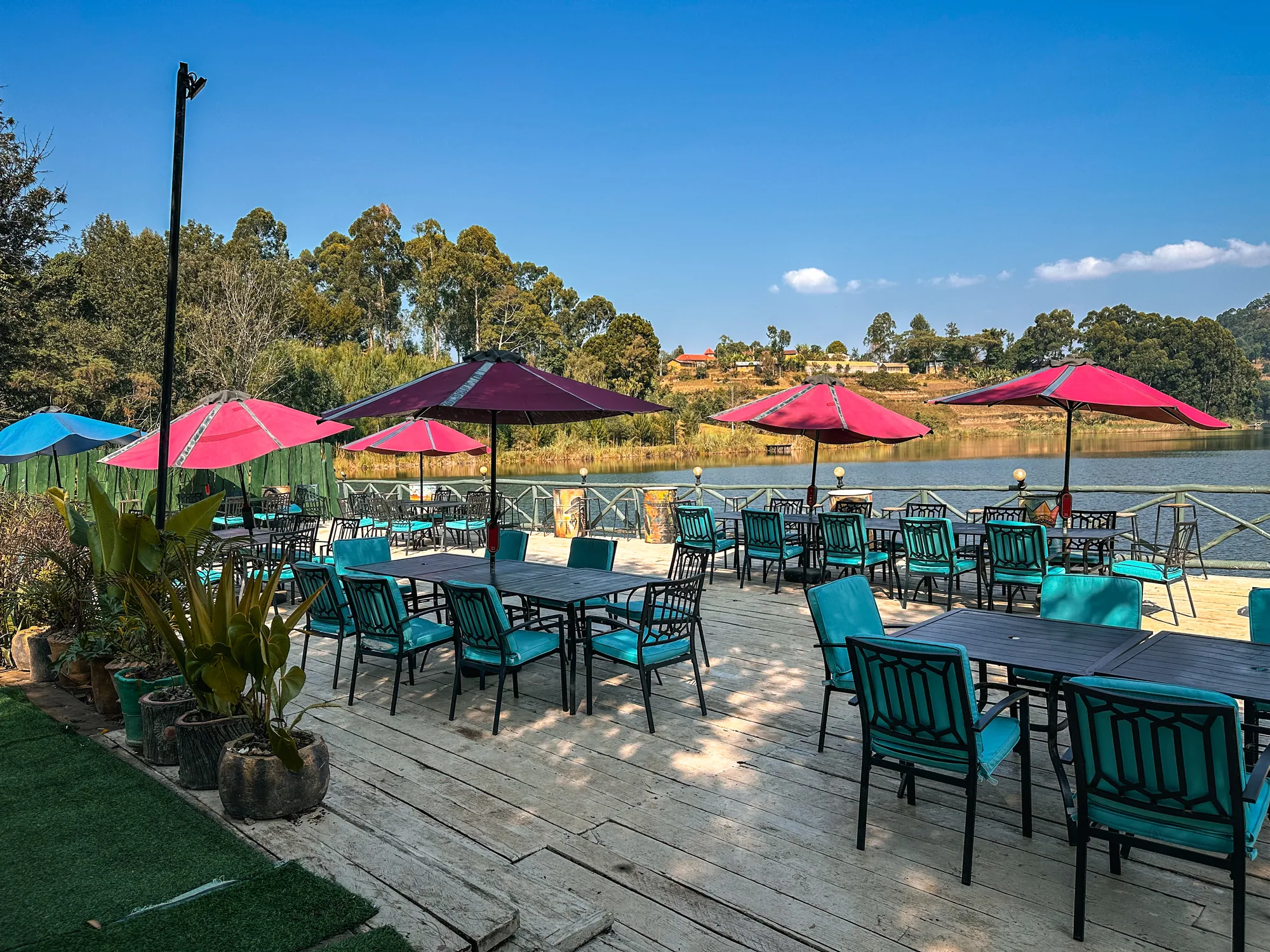 A row of tables under pink and purple parasols on the lakeside deck