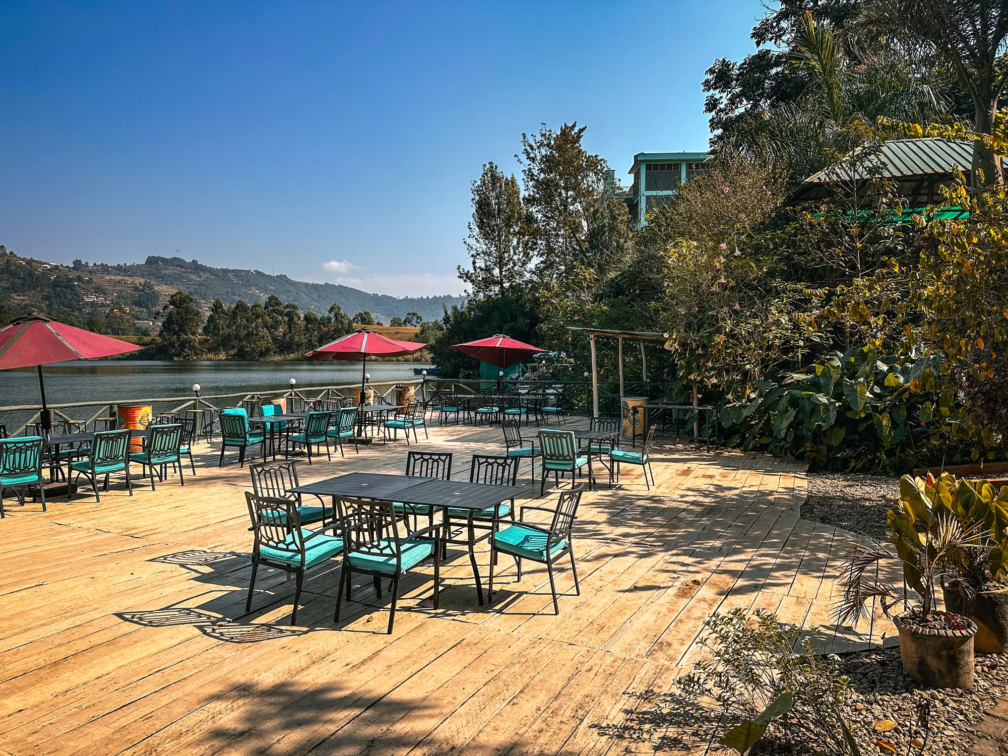 The wide timber deck with red parasols and scattered tables above the shoreline