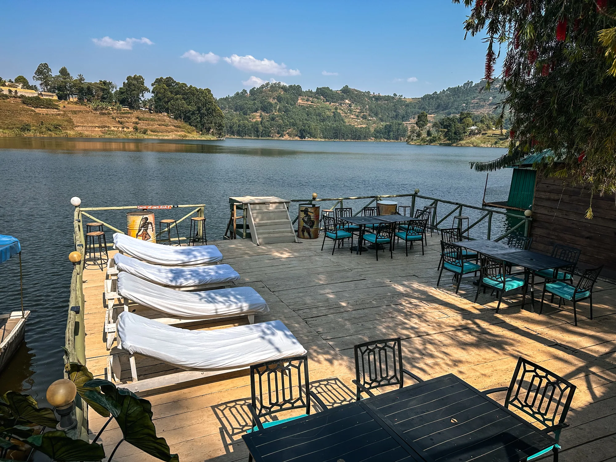 Sun loungers with folded towels along the jetty deck, the lake and hills beyond