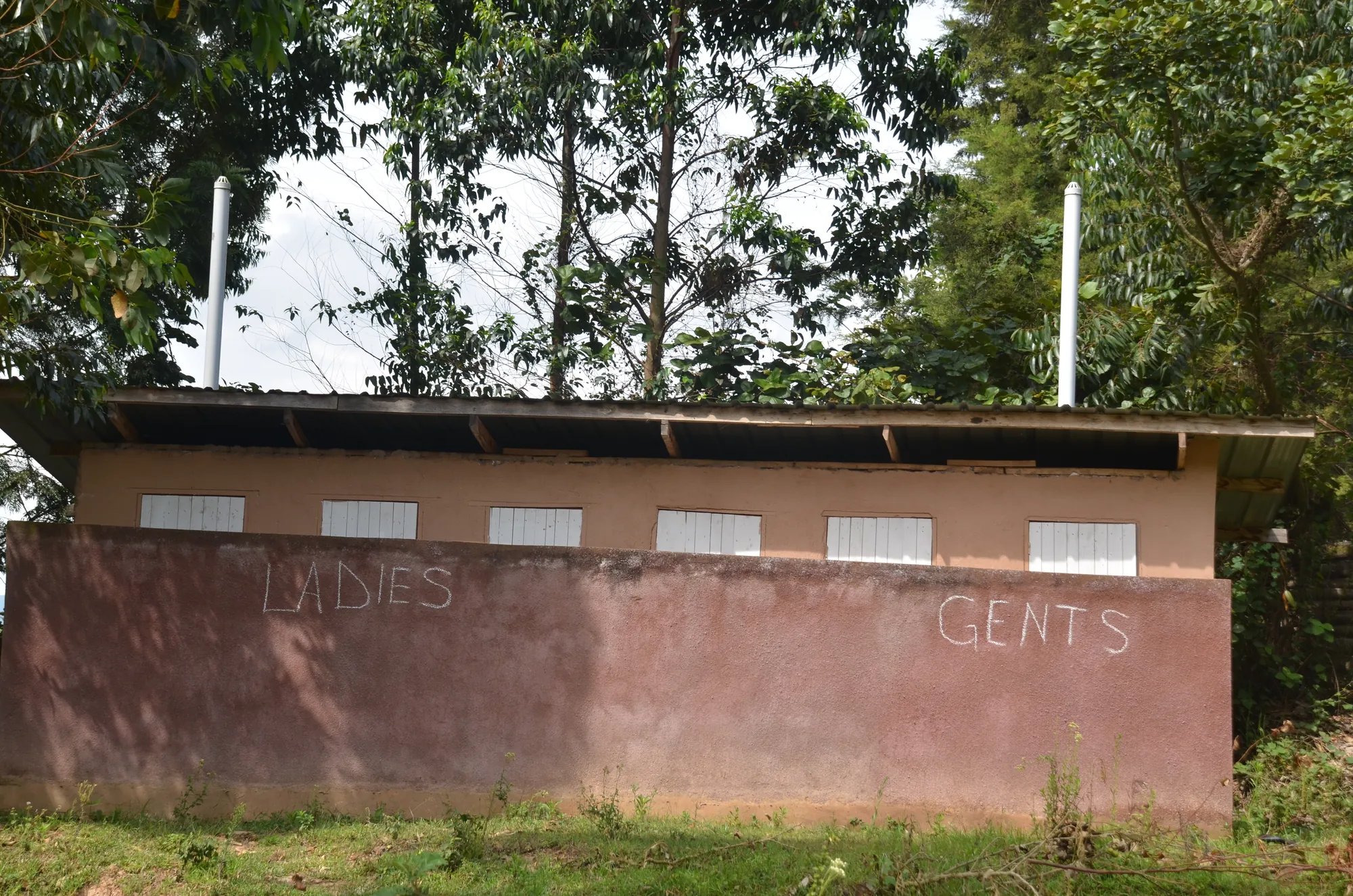 The latrine block with ladies' and gents' entrances marked on the rendered wall