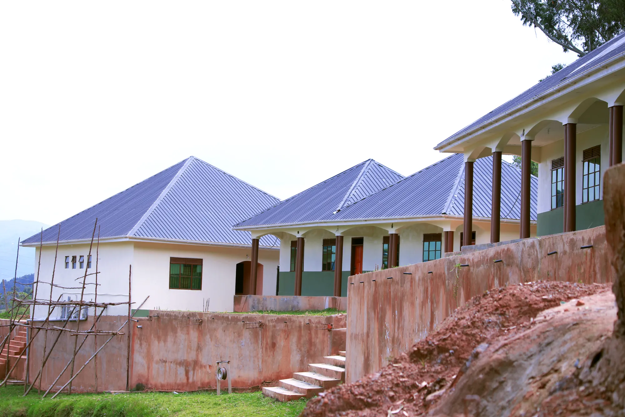 A row of new classroom blocks with purple-blue roofs behind a retaining wall