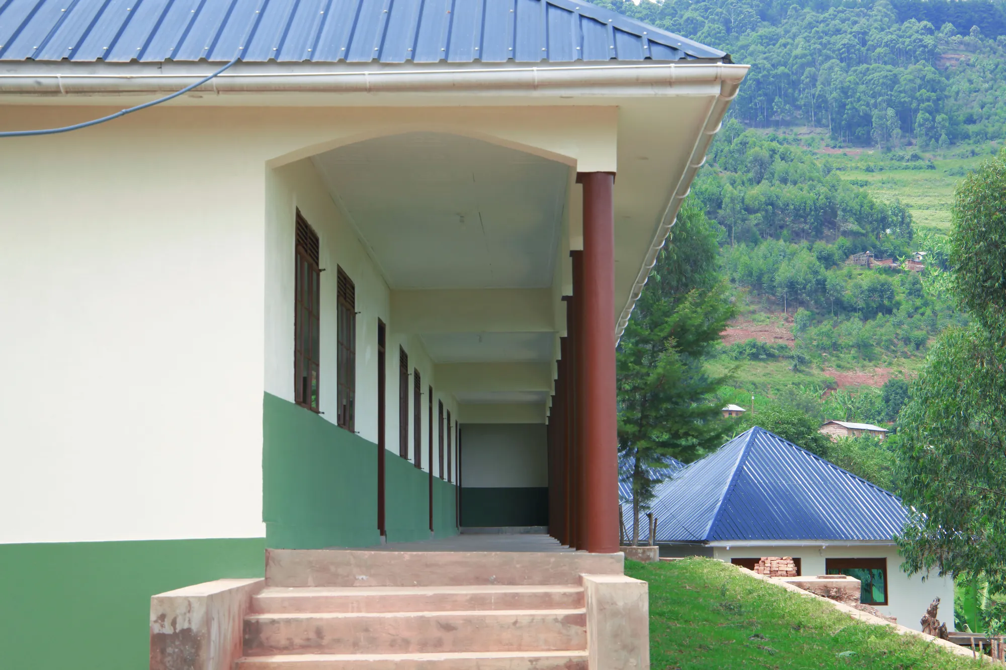 The covered walkway and steps of a classroom block, looking out to the hills