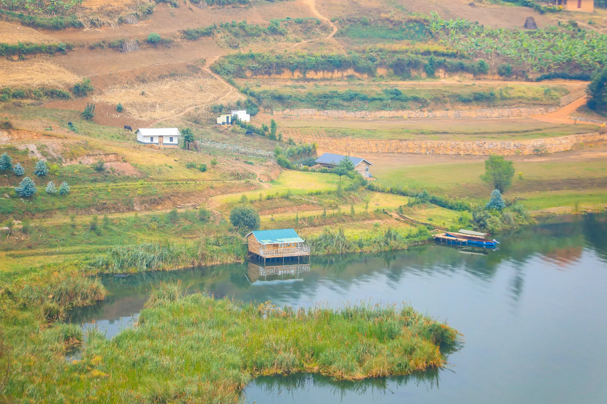 Lake Bunyonyi with boats moored at a landing and cultivated hillsides behind