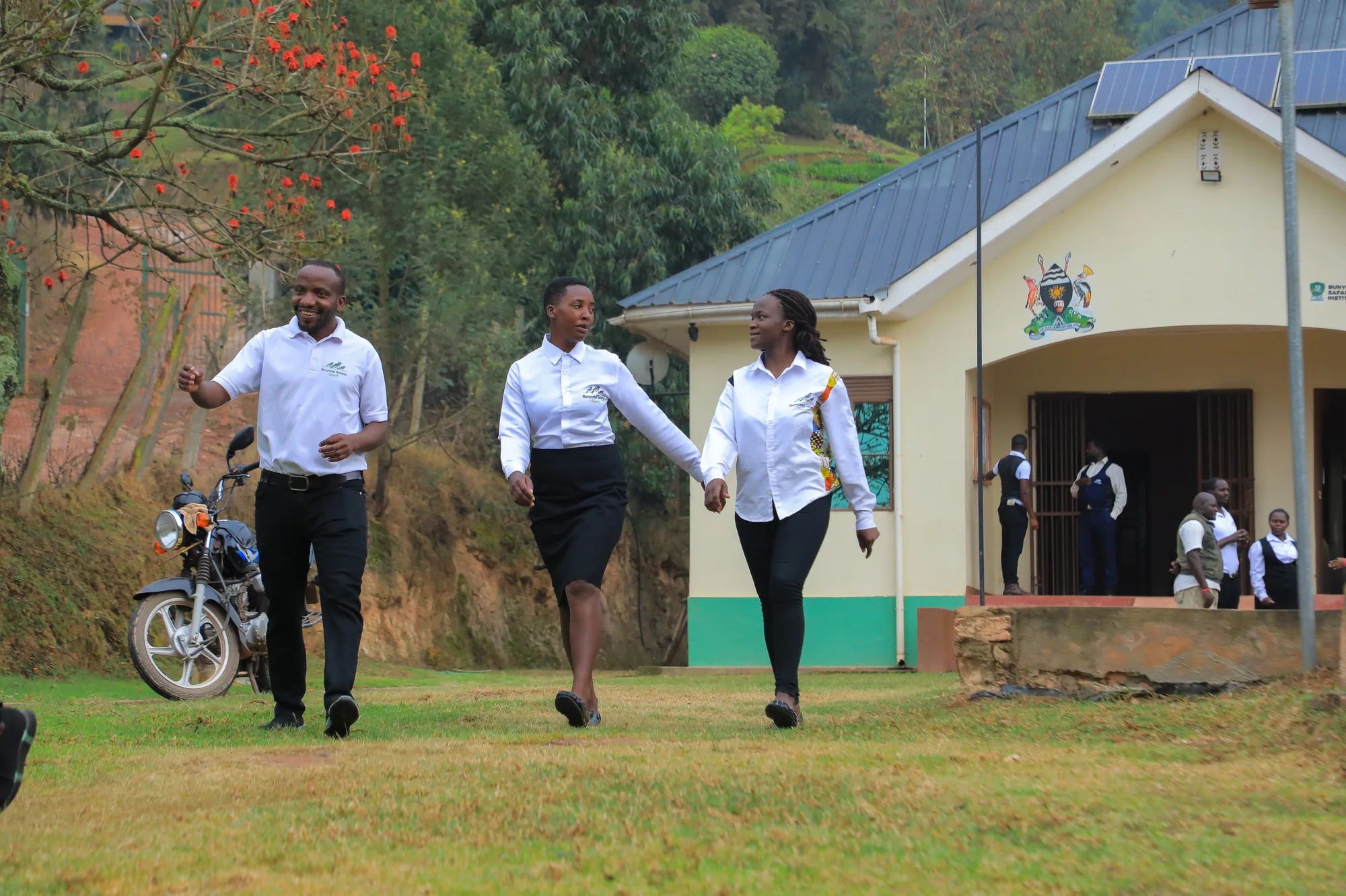 A staff member and two students walking on the lawn in front of the institute entrance