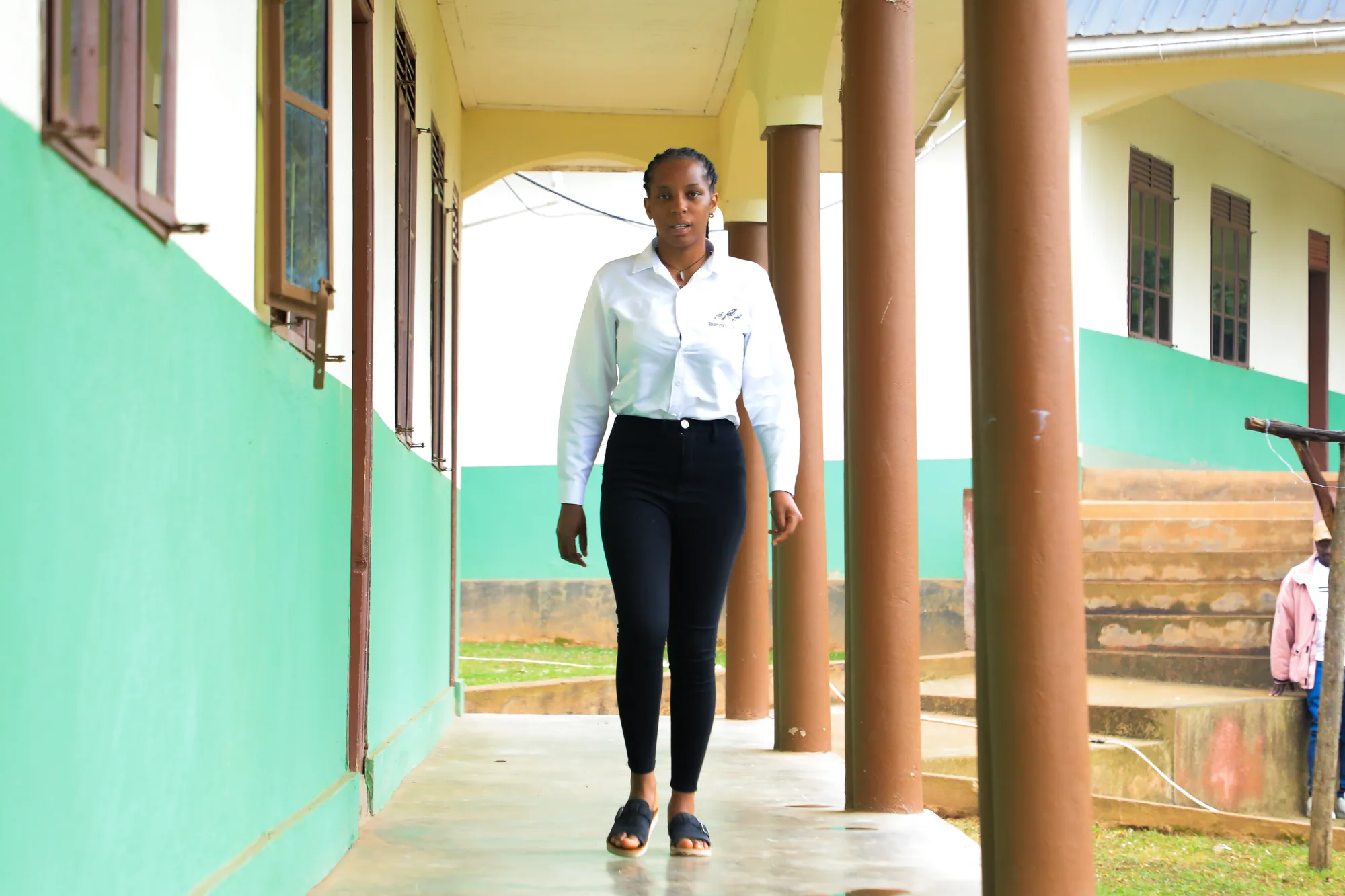A student walking towards the camera along the veranda of a classroom block