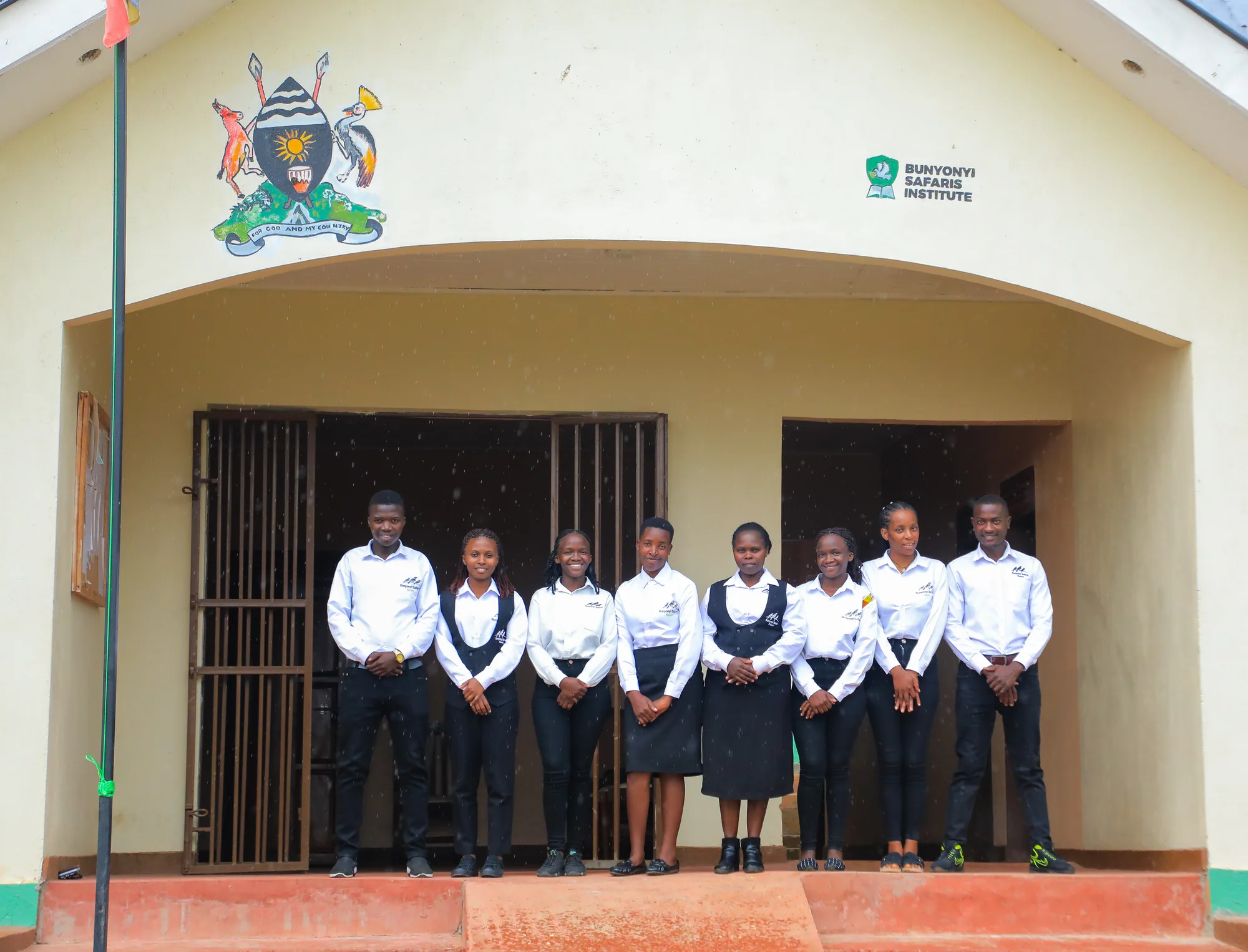 Students standing under the entrance porch below the painted coat of arms and institute sign