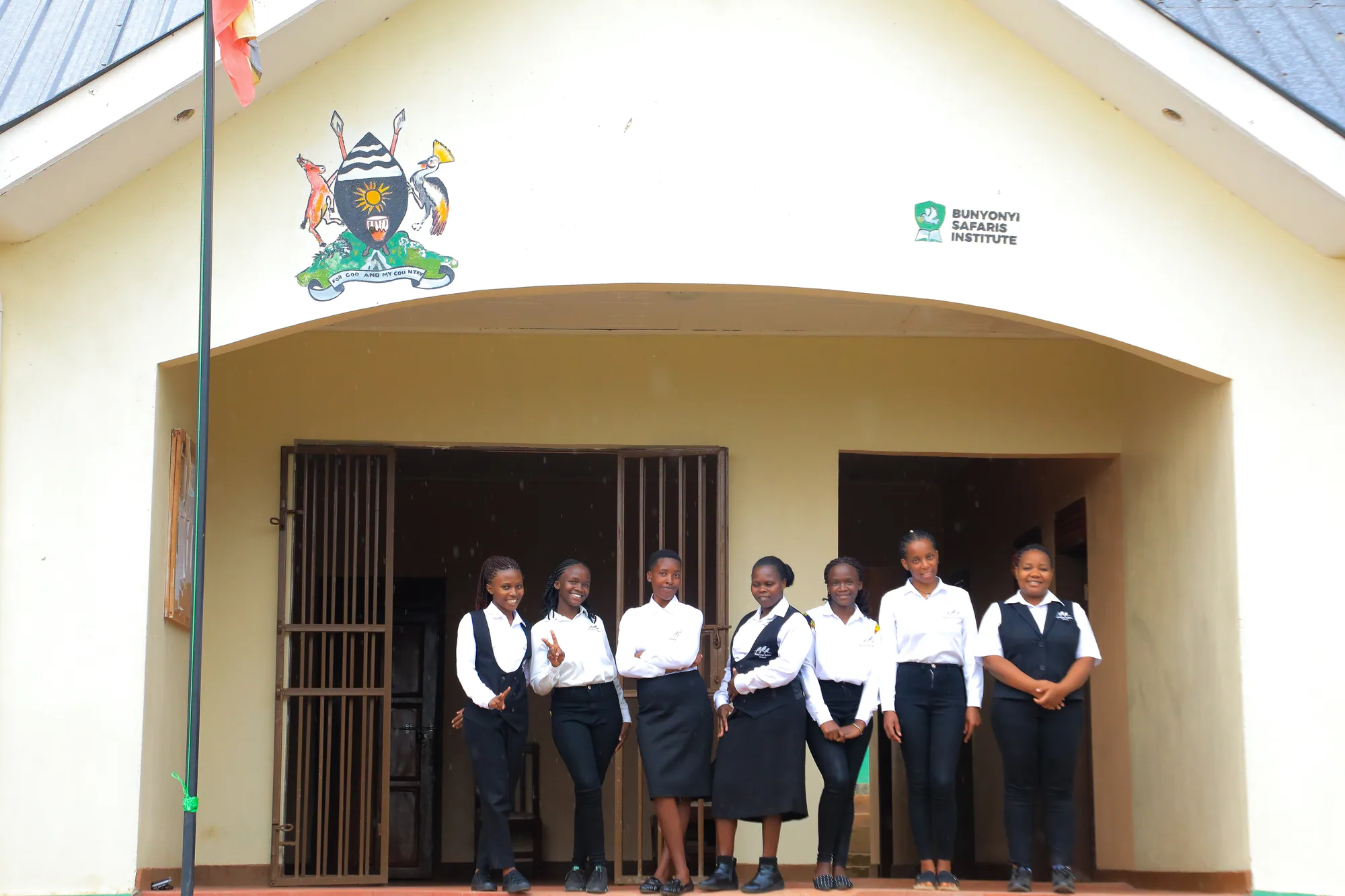 Students standing in the entrance porch under the coat of arms and institute sign