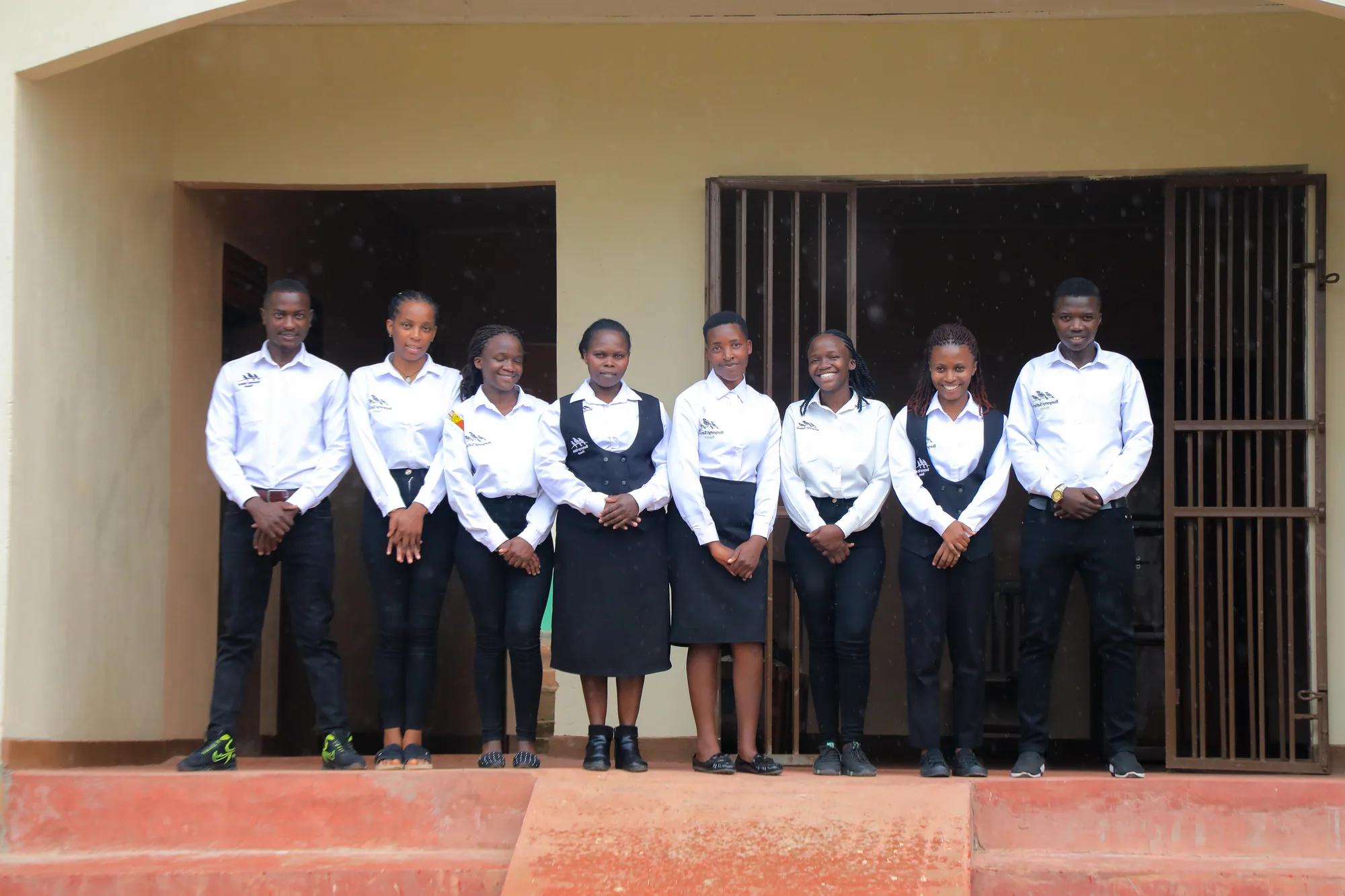 Eight students standing shoulder to shoulder on the institute entrance steps