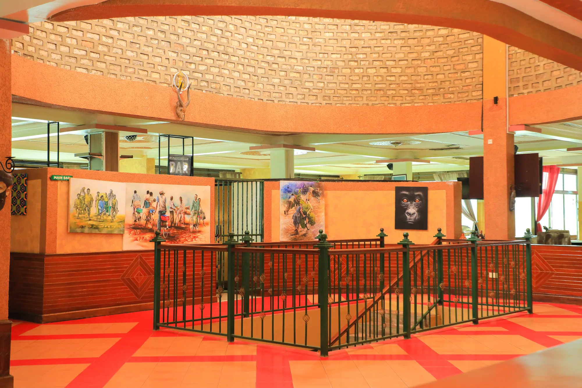 A large hall interior with a woven ceiling, orange tiled floor and railed dance area