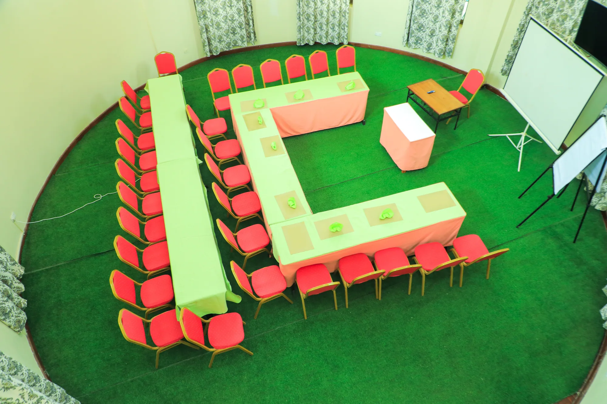 The conference room seen from above, tables in a U-shape on green carpet