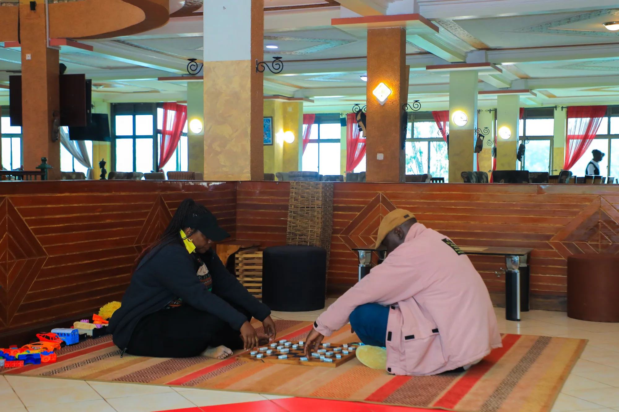 Two guests sitting on a rug playing a board game in the lounge