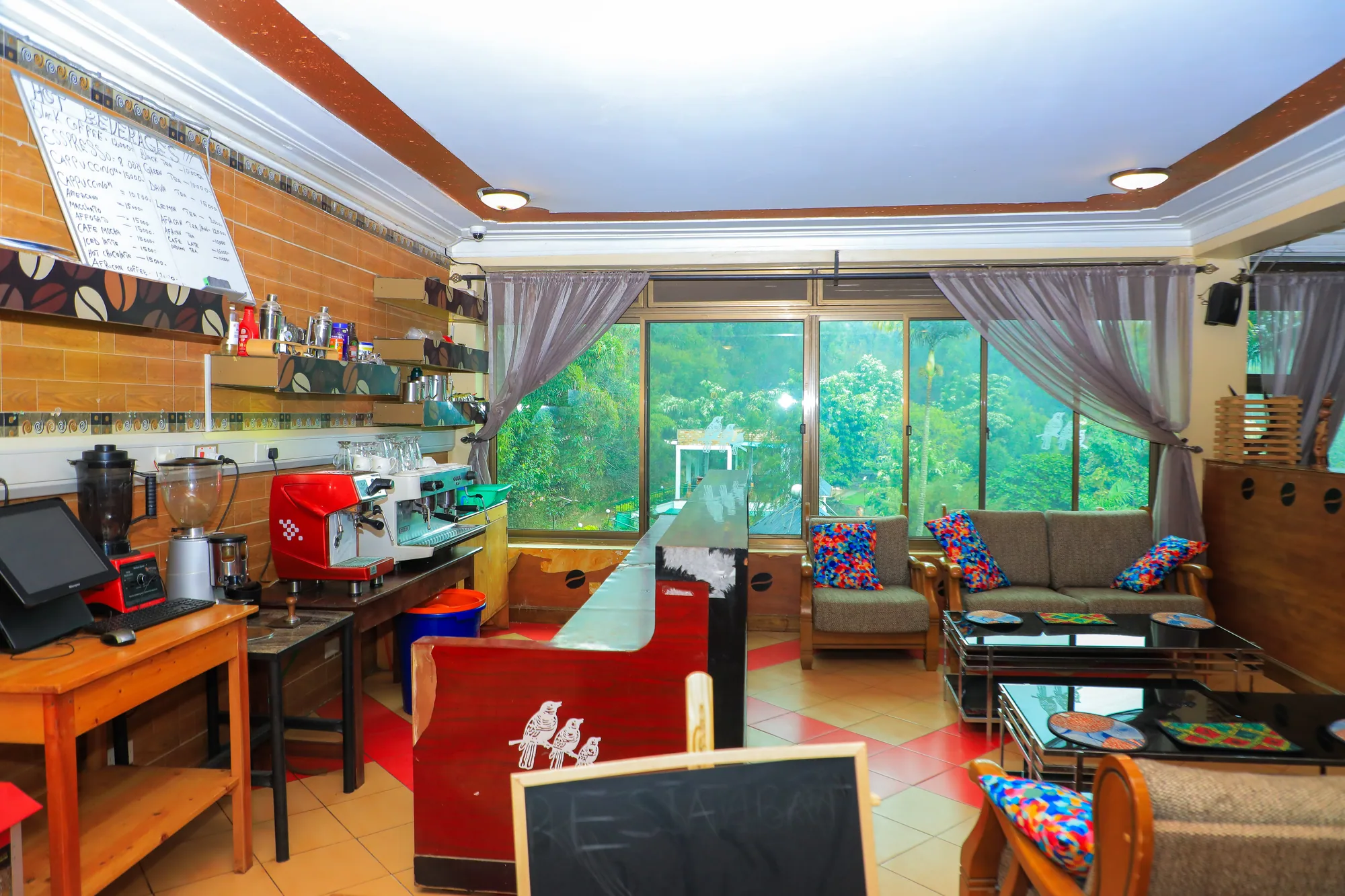 A family room with a coffee counter, sofas and toys beside floor-to-ceiling windows