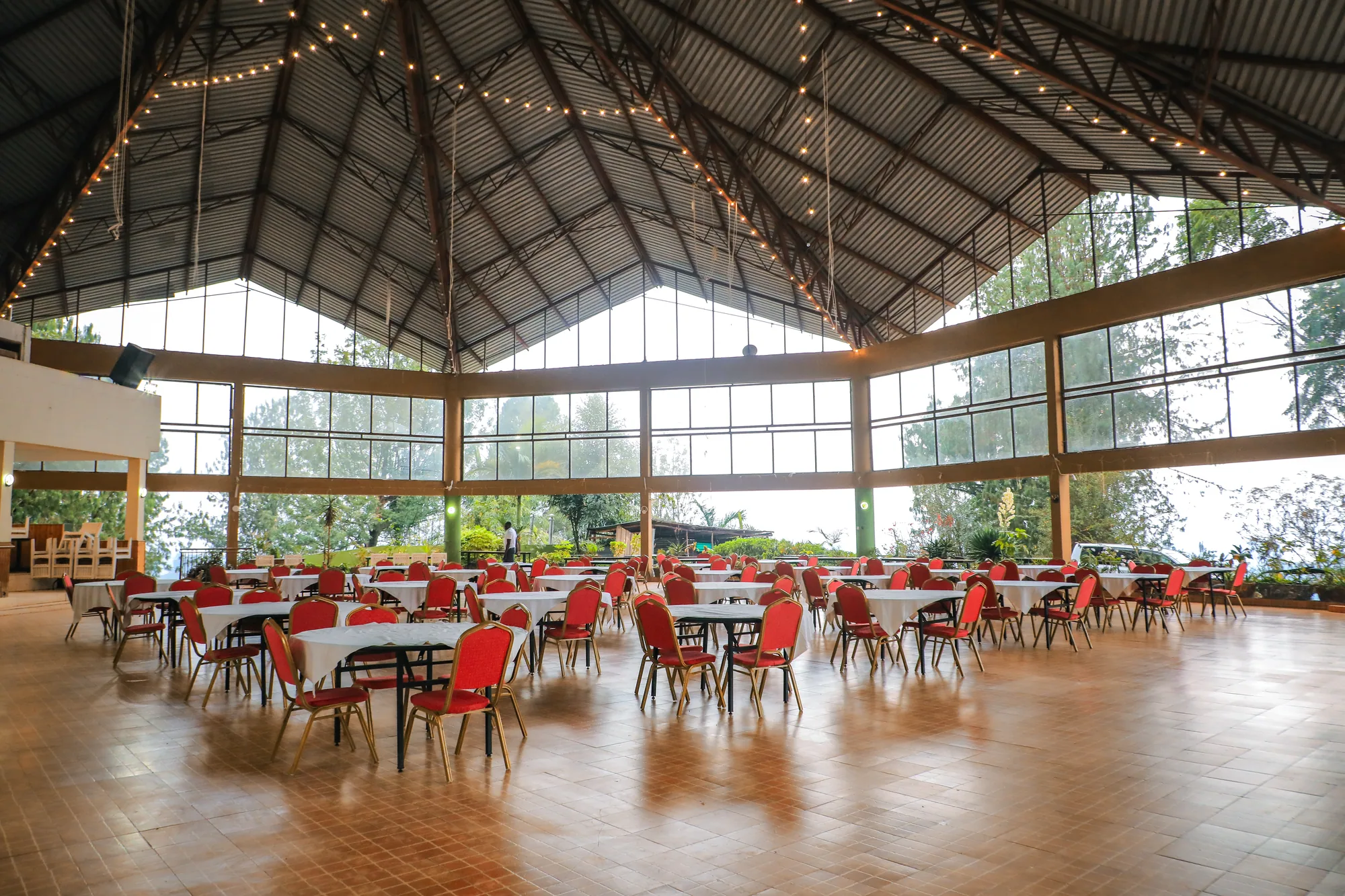 The events hall under its timber roof structure, laid with round tables and red chairs