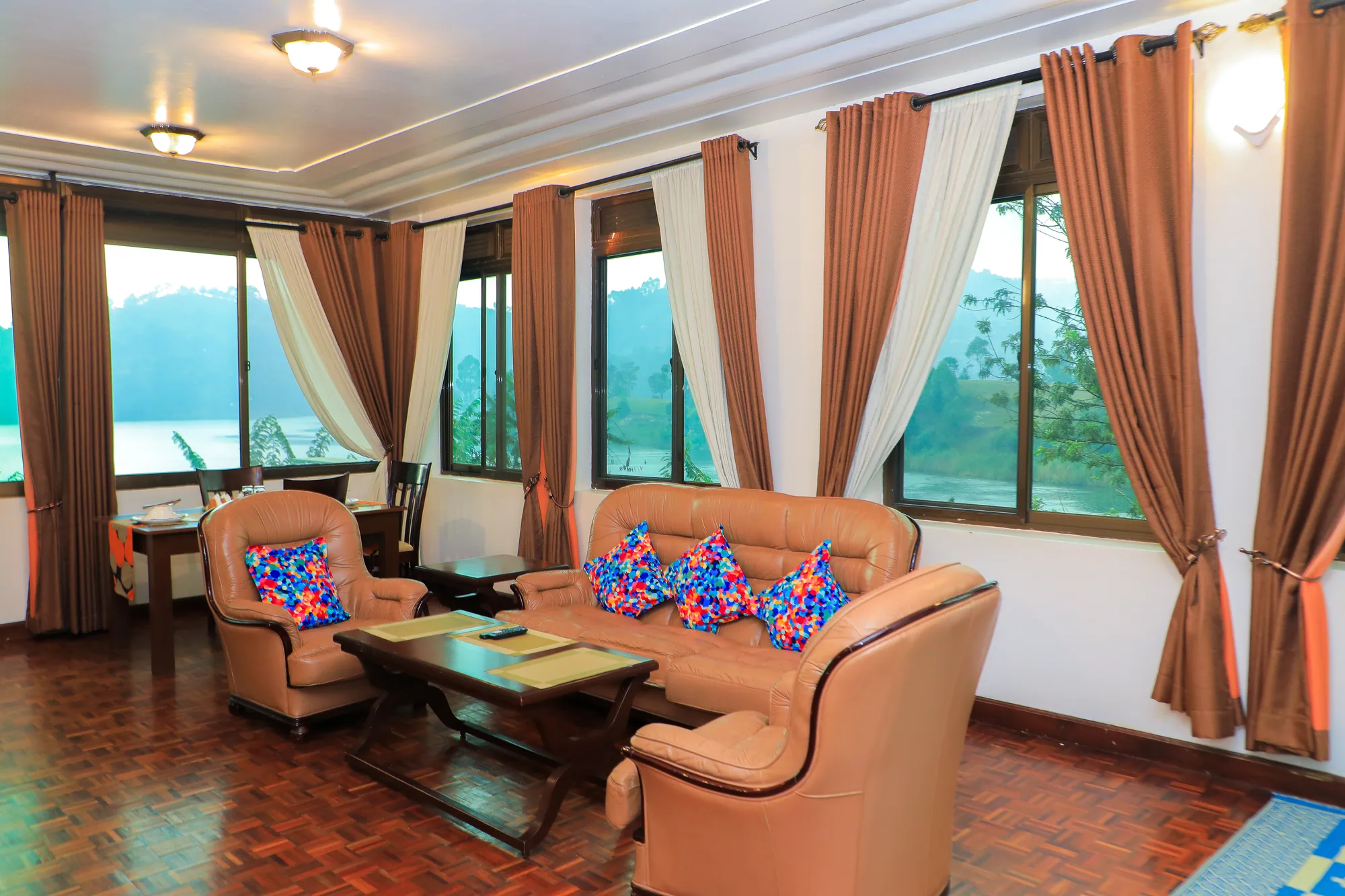 A suite lounge with two armchairs, patterned cushions and curtained windows over the lake