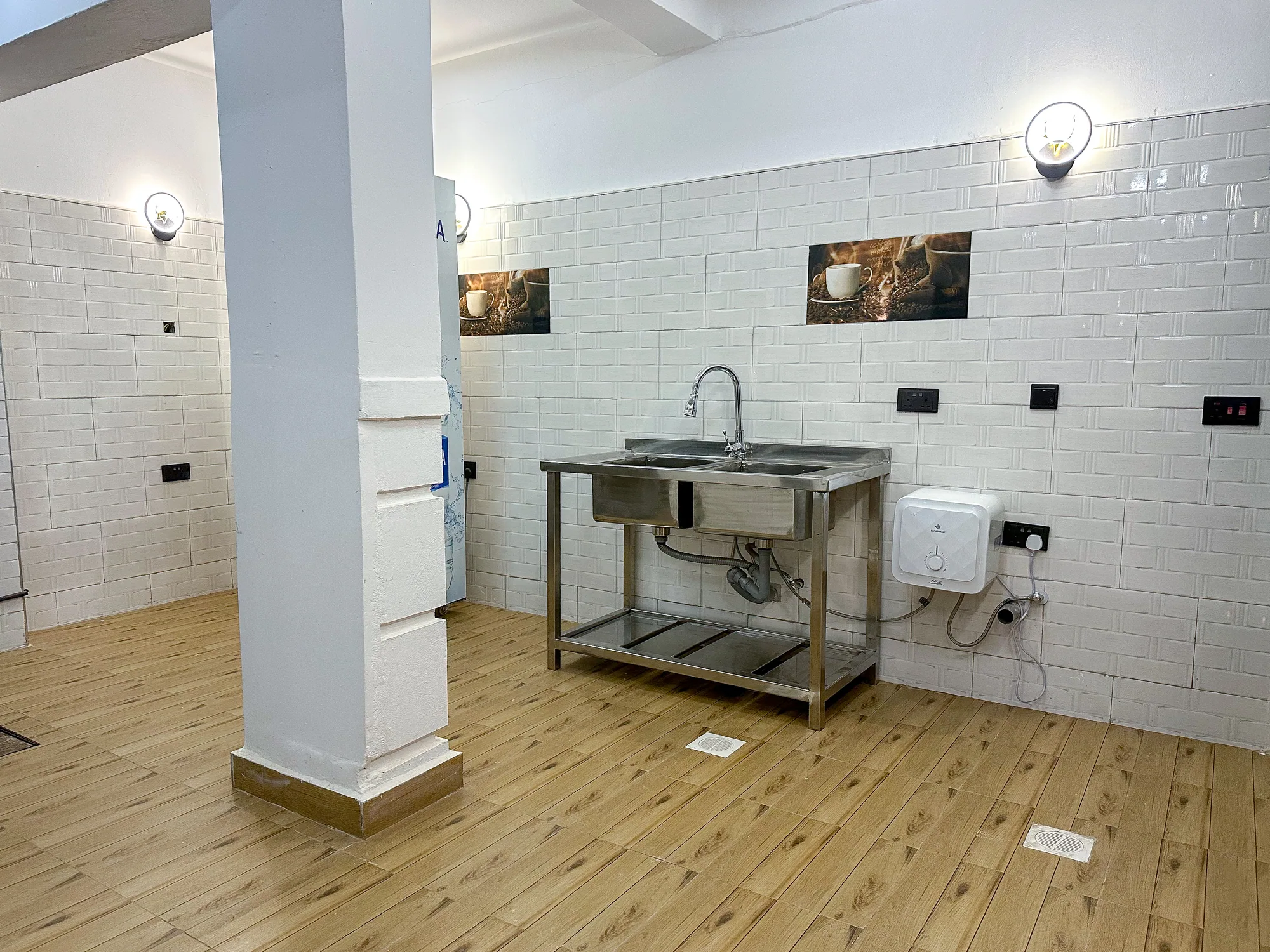 A stainless steel sink unit against the tiled wall of the empty kitchen
