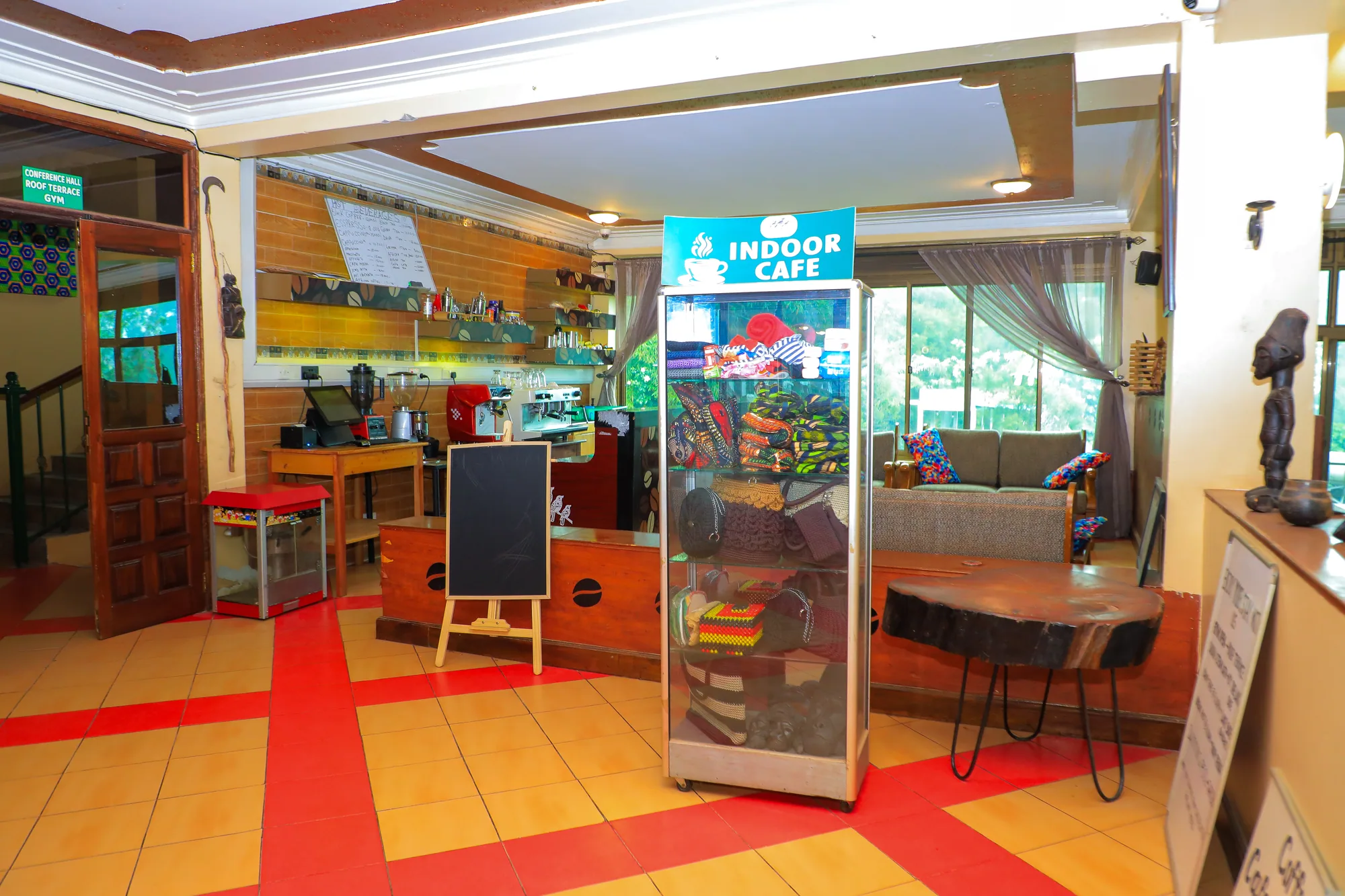 The indoor café with a drinks fridge, chalkboard and seating on a red patterned floor
