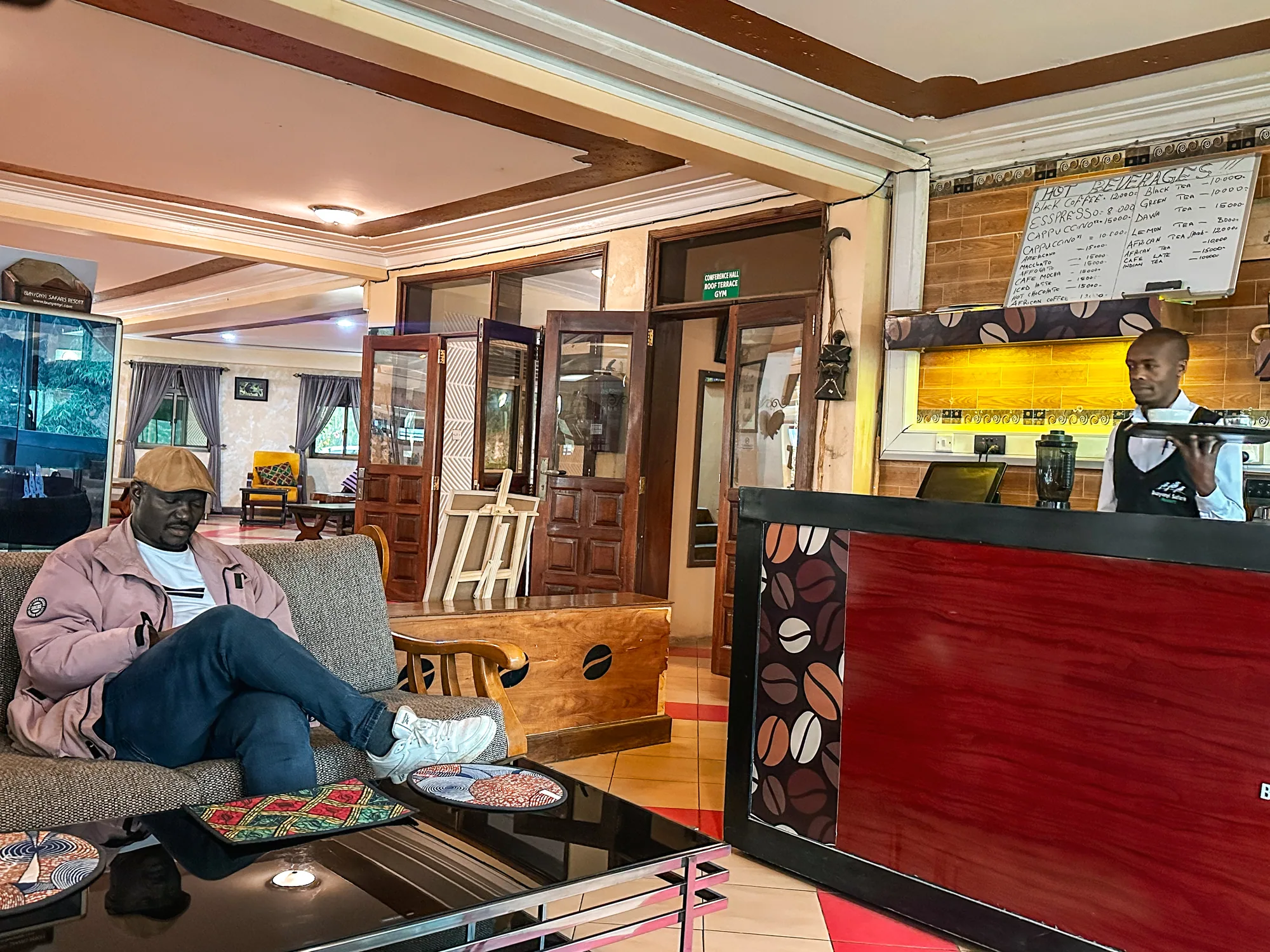 A guest reading on a sofa in the café lounge while a waiter stands at the counter