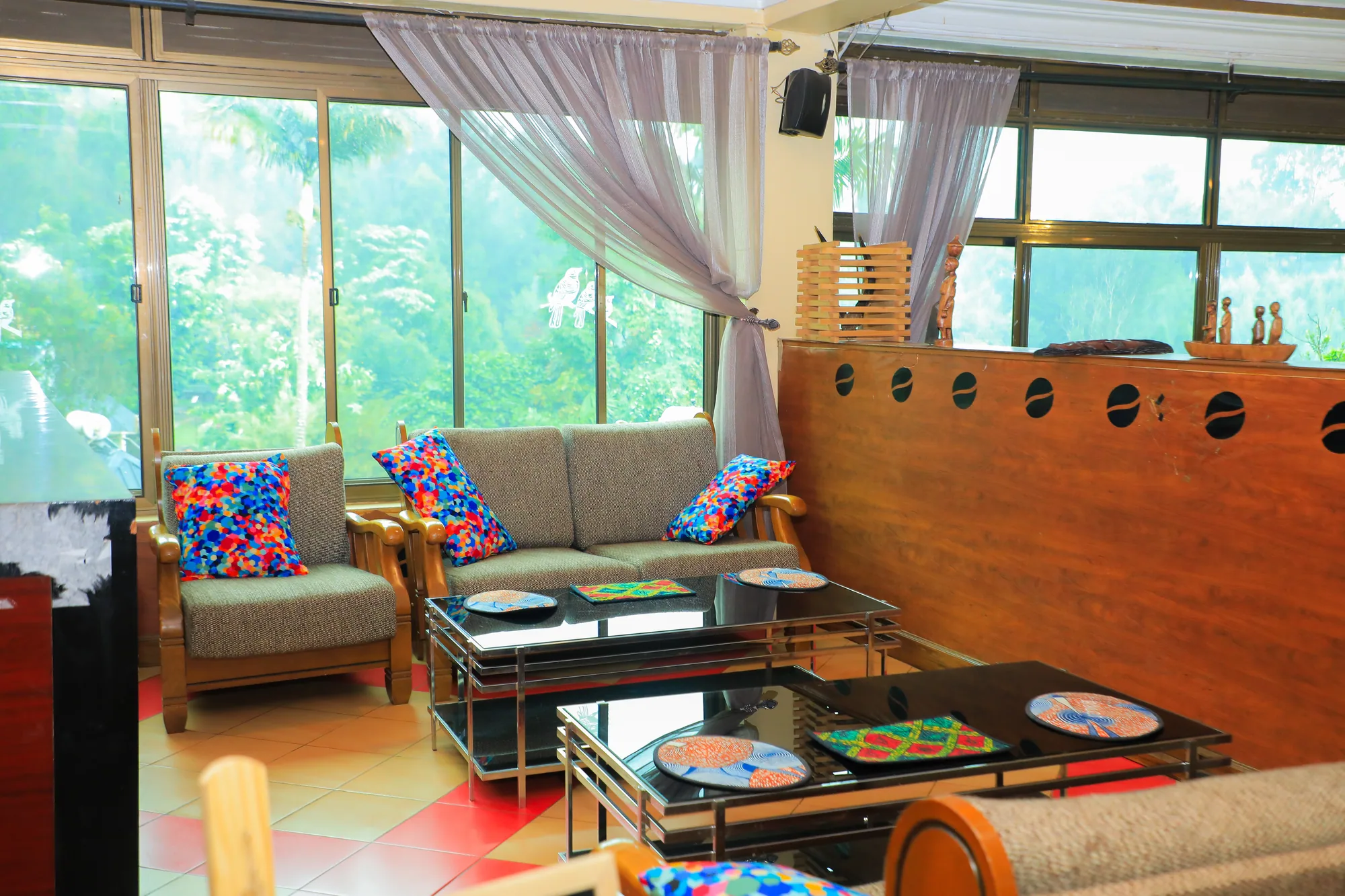 A lounge corner with sofas, printed cushions and a foosball table by the tall windows